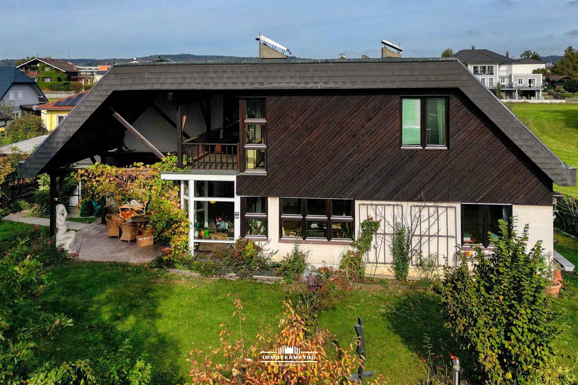 Rückansicht des Hauses mit Garten und Blick auf die umliegende Landschaft und Siedlung.