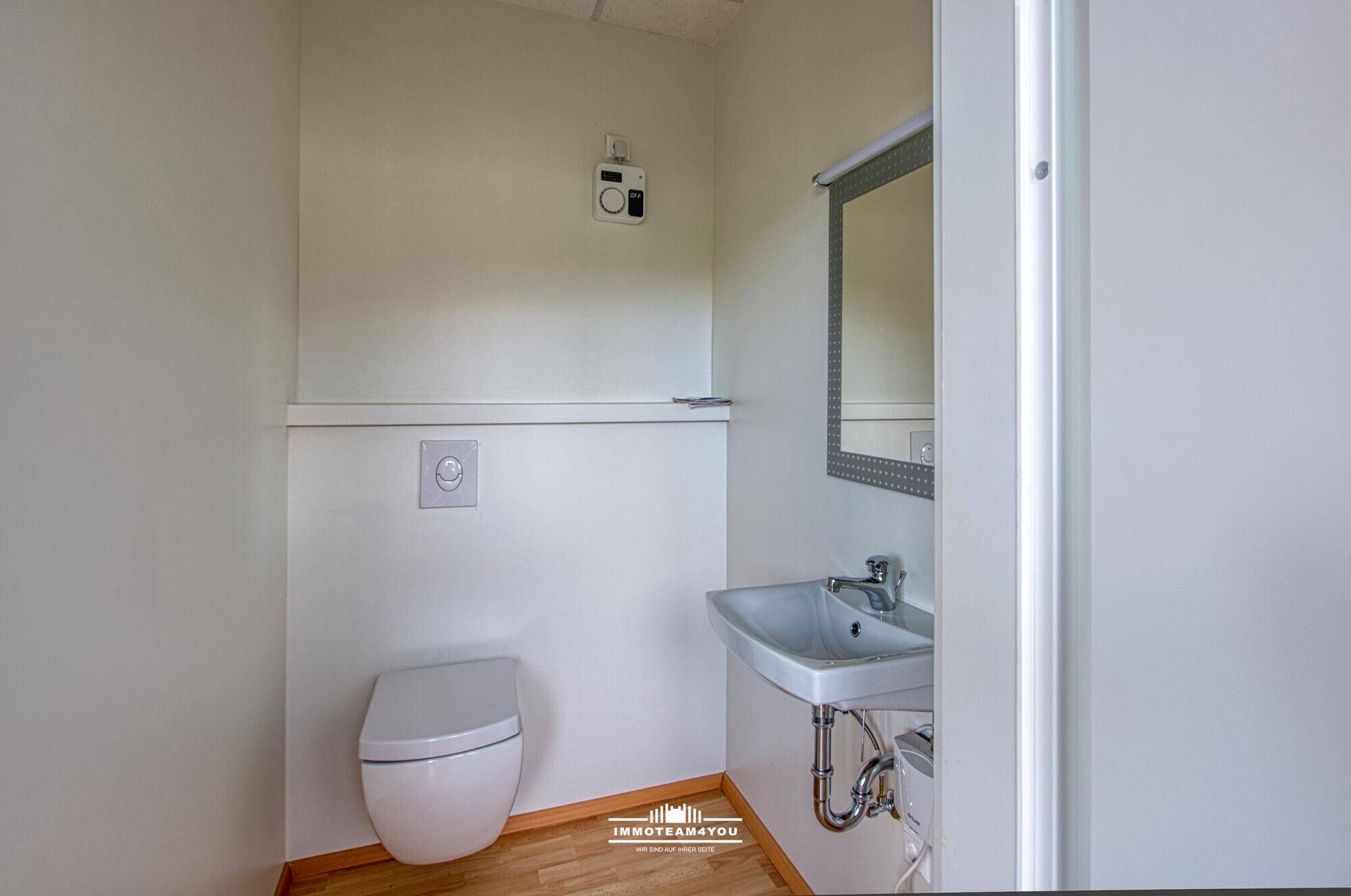 Kleine Gästetoilette mit wandhängendem WC, Waschbecken und Spiegel in einem hellen, funktionalen Design.