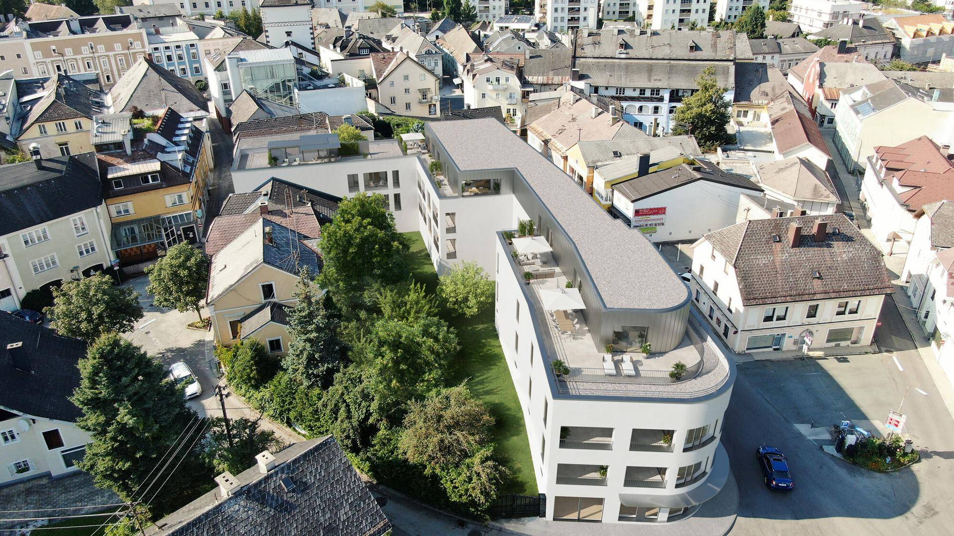 Luftaufnahme eines modernen Gebäudekomplexes mit begrünten Innenhöfen in städtischer Umgebung.