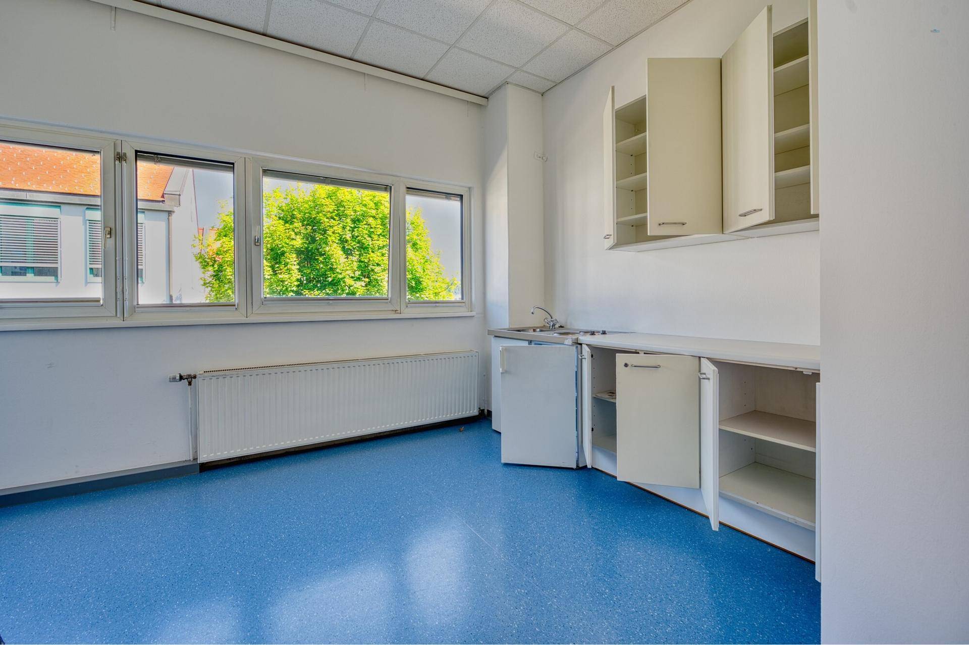 Kleine Teeküche mit Spülbecken, Schränken und Fenstern mit Blick ins Grüne, ideal für Pausen.