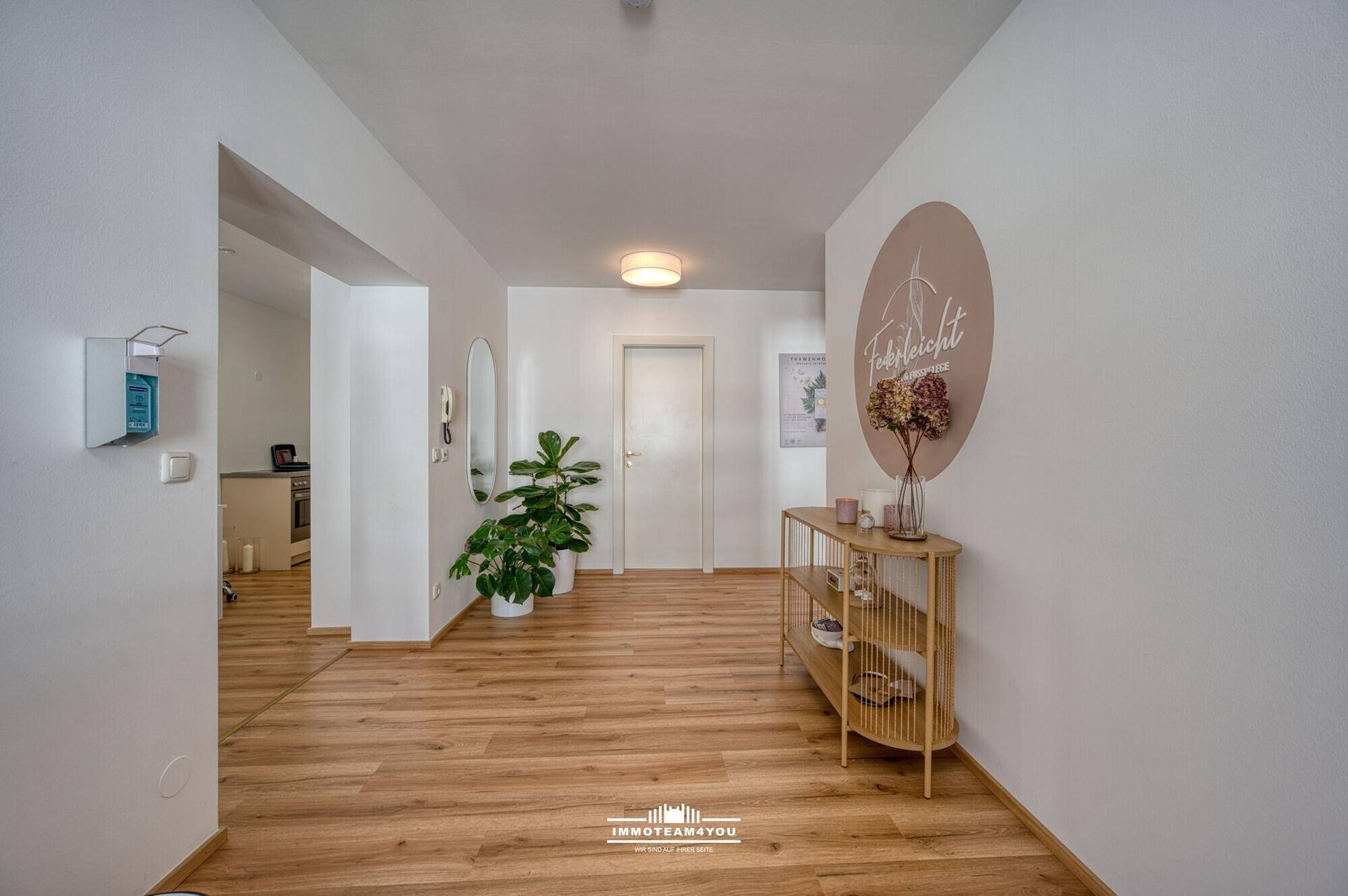 Eingangsbereich mit Holzfußboden, heller Beleuchtung und Zugang zu weiteren Räumen.