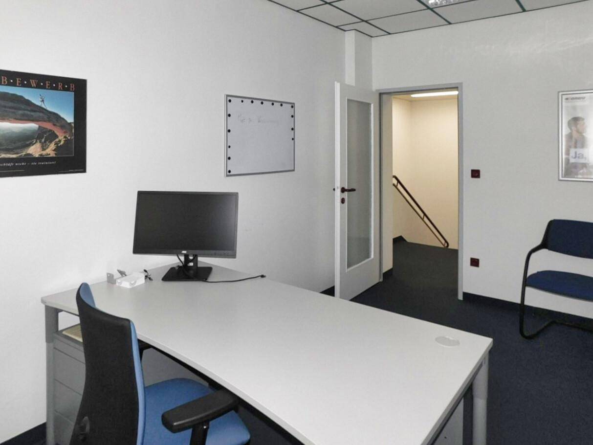 Einzelbüro mit Schreibtisch, Bürostuhl und Zugang zu einem Treppenhaus, ideal für konzentriertes Arbeiten.
