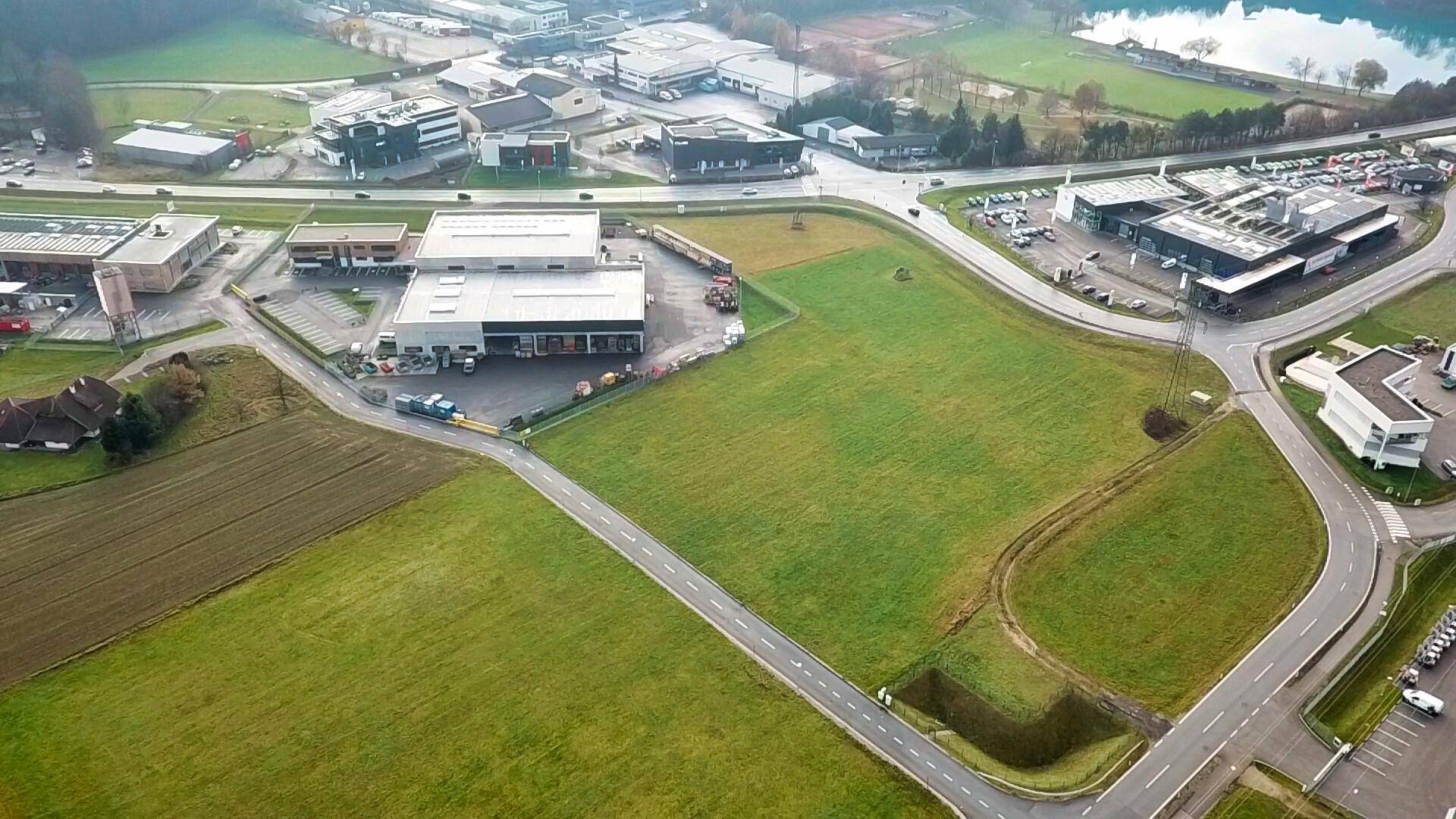 Weitläufige Luftaufnahme eines grünen Grundstücks mit angrenzenden Straßen und Gewerbegebieten.
