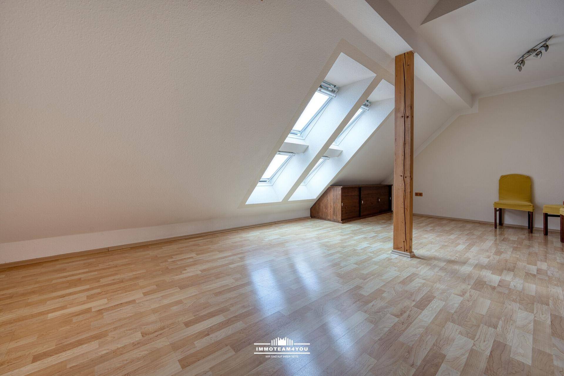 Geräumiger Dachbodenraum mit Holzboden, Dachfenstern und sichtbarem Holzbalken.