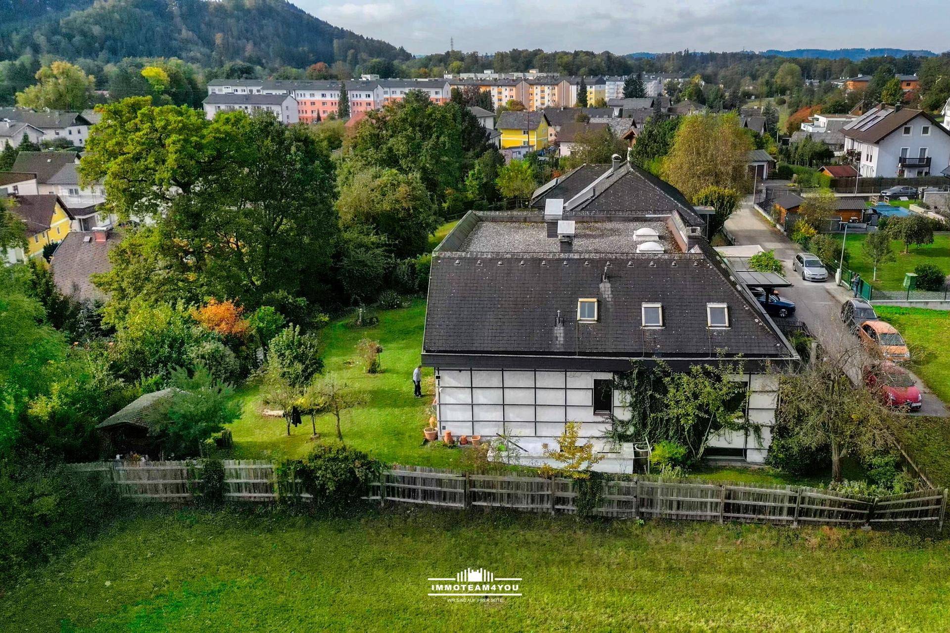 Luftaufnahme des Anwesens mit großem Garten und Blick auf die umliegende Wohnsiedlung und Landschaft.