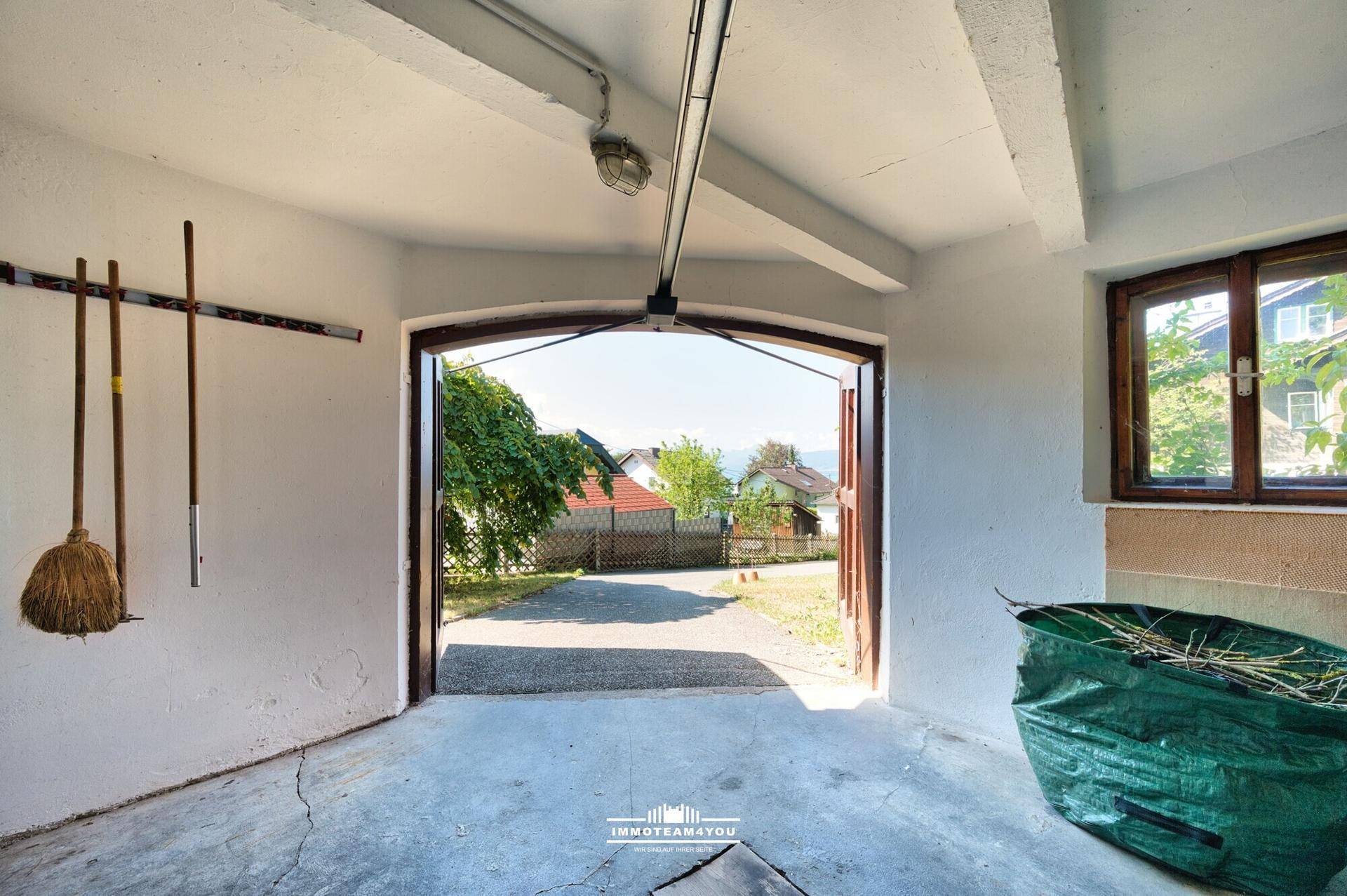 Garage mit offenem Tor, Blick auf die Einfahrt und den Außenbereich des Grundstücks.