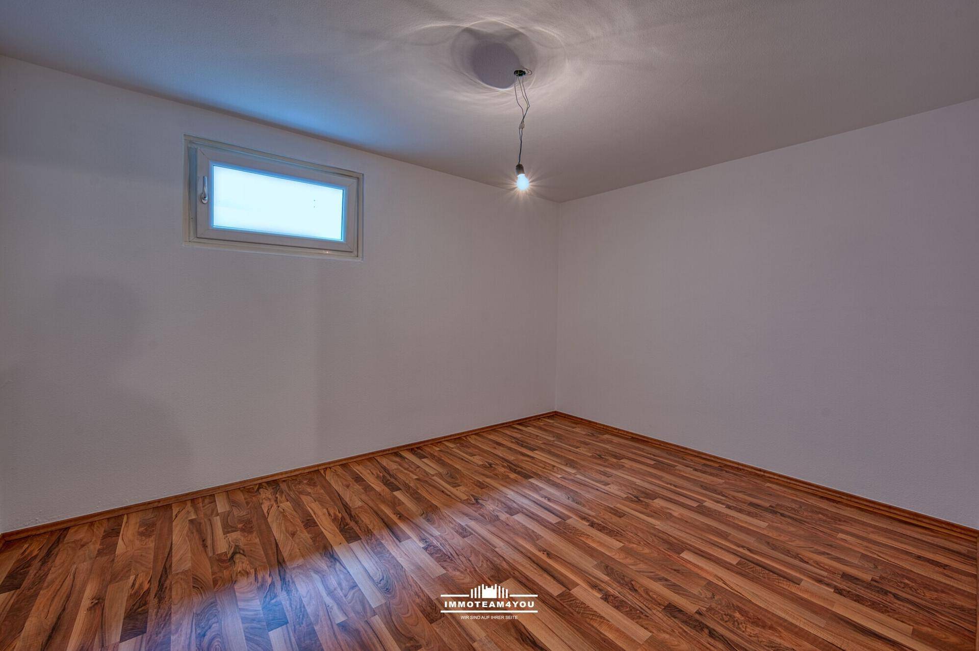 Helles Zimmer im Dachgeschoss mit Laminatboden und kleinem Fenster.