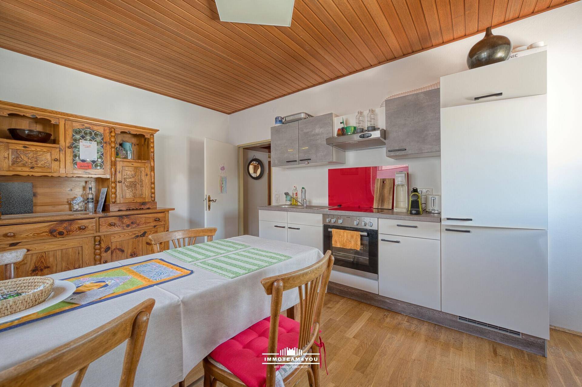 Gemütliche Wohnküche mit Holztisch, traditionellem Schrank und einer Holzdecke.