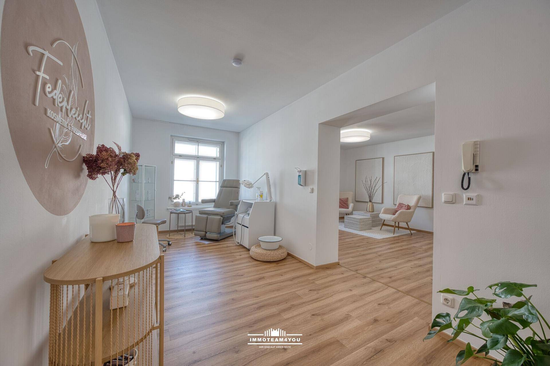 Heller Raum, eingerichtet als Kosmetikstudio, mit großem Fenster und Holzfußboden.