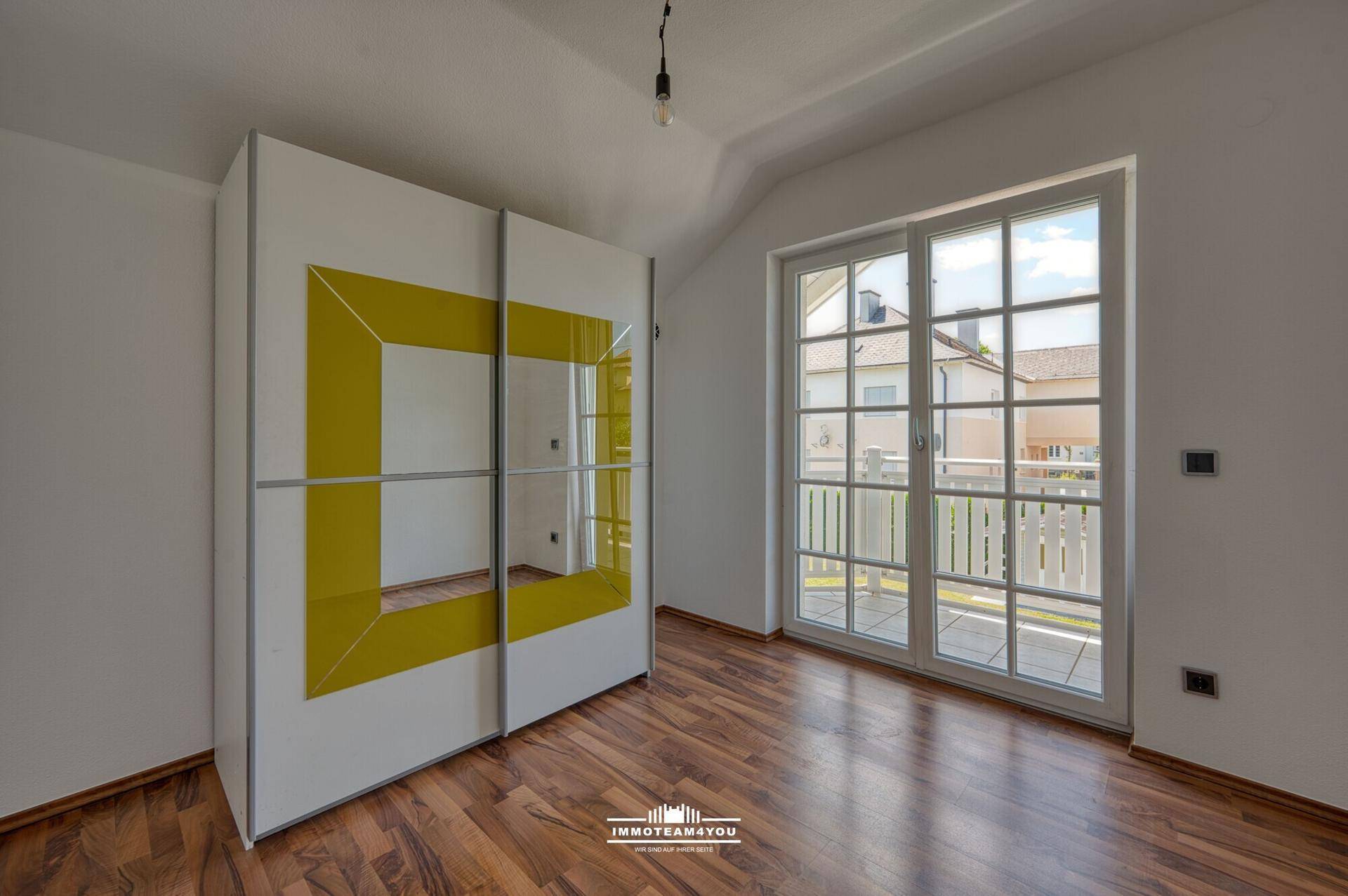 Schlafzimmer im Dachgeschoss mit Laminatboden, Schrank und Balkonzugang.