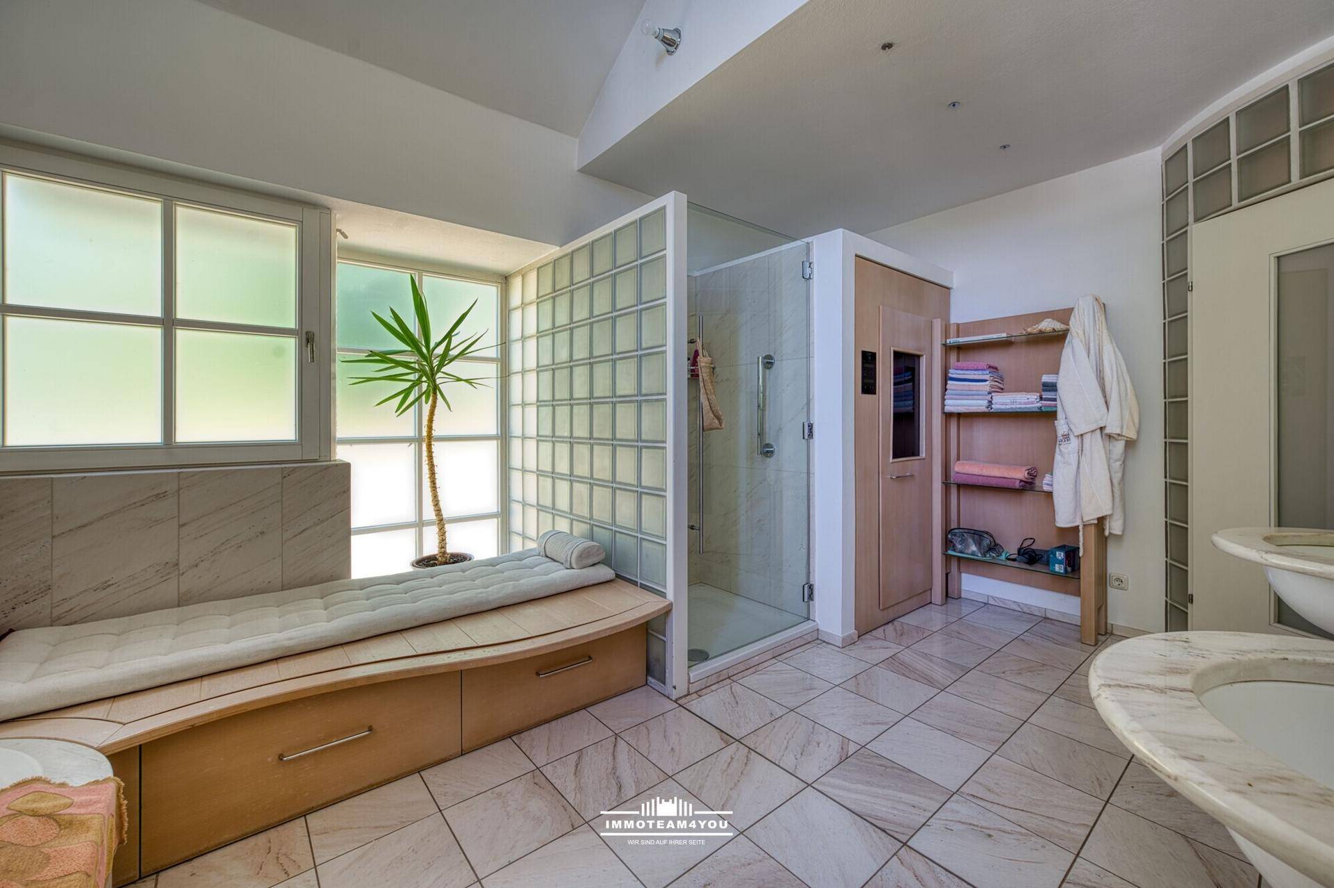 Geräumiges Badezimmer mit Wellnessbereich, Dusche, Doppelwaschbecken und viel Tageslicht.