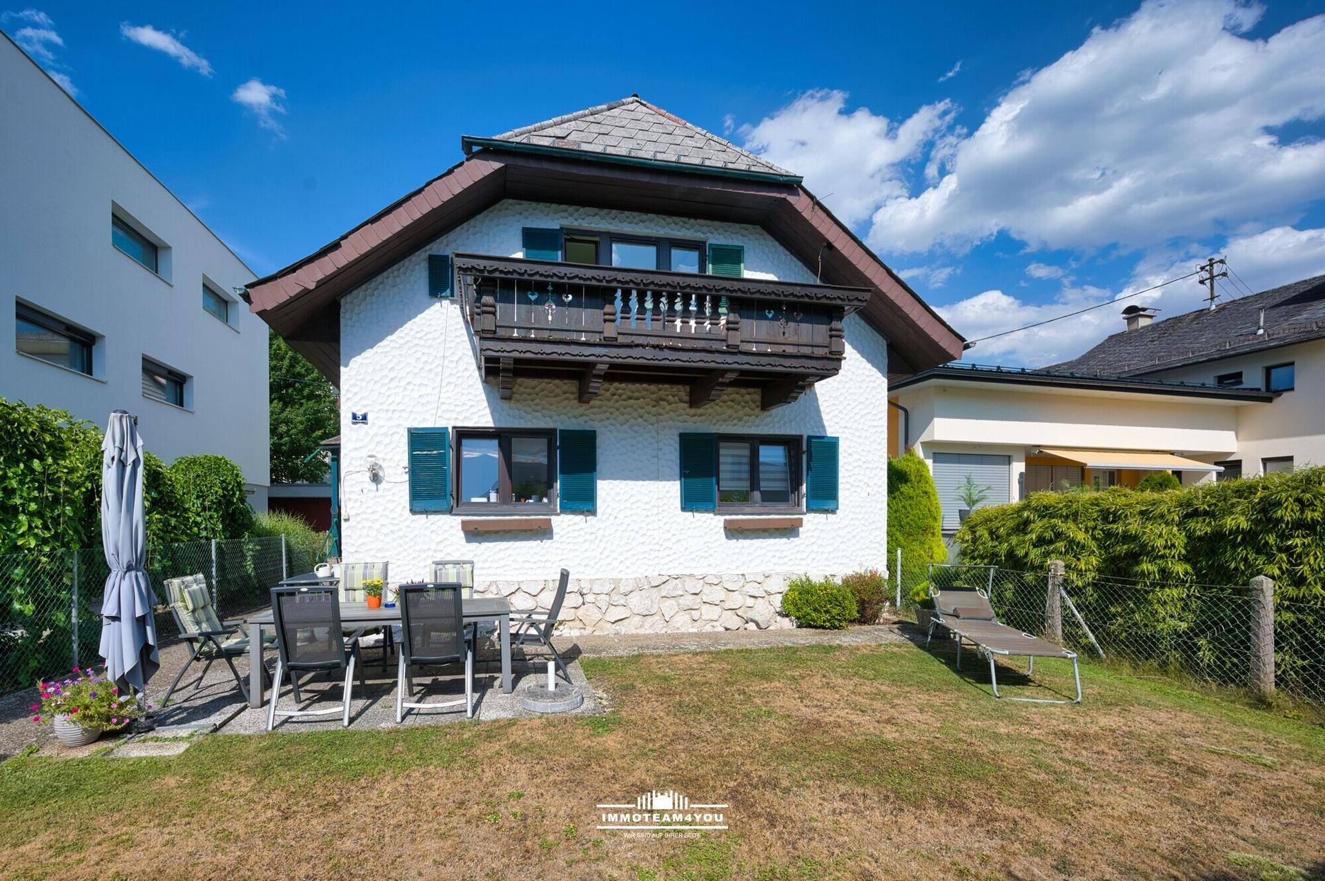 Gepflegter Gartenbereich mit Terrasse und Rasenfläche hinter dem traditionellen Wohnhaus.