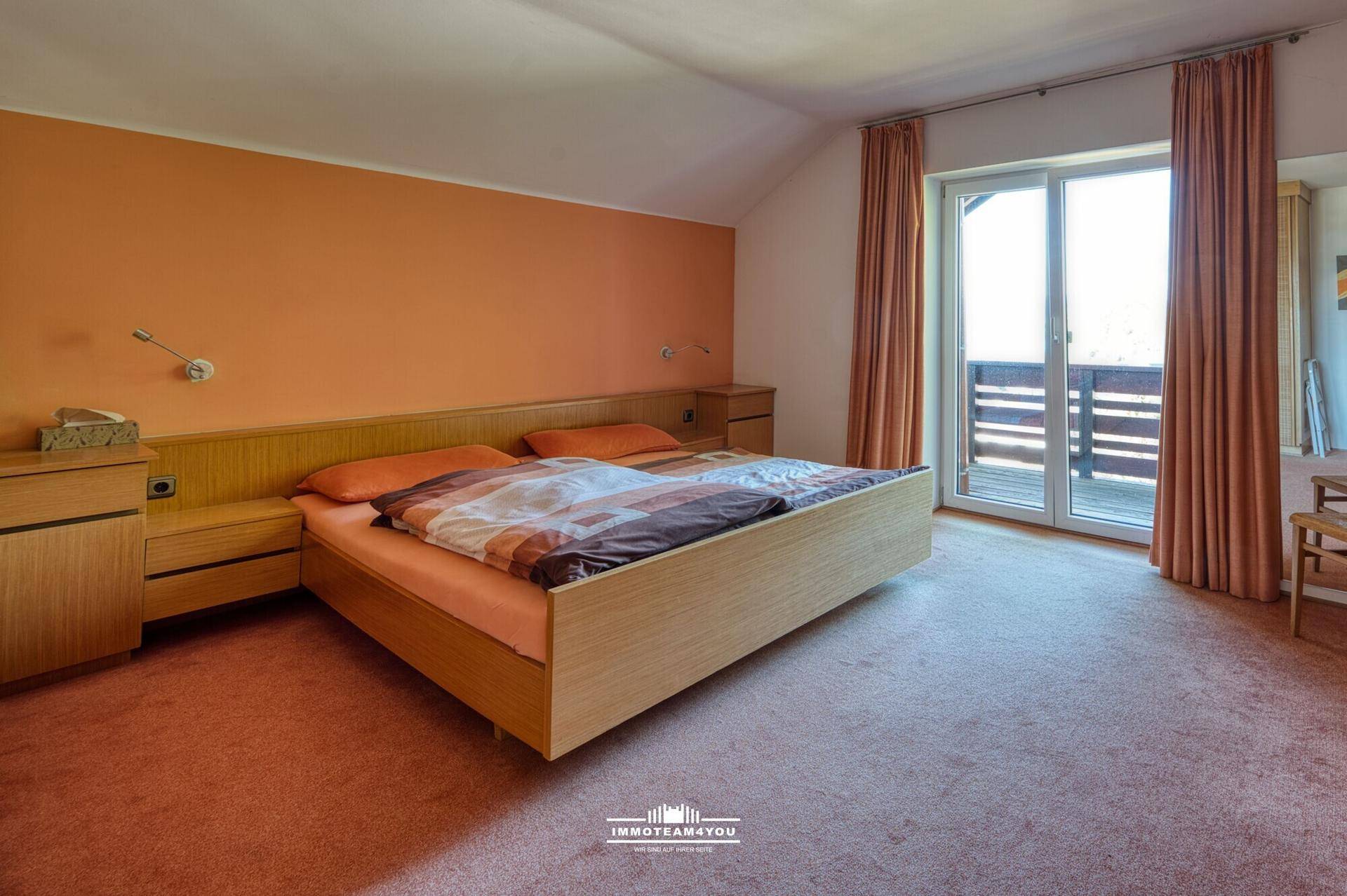 Gemütliches Schlafzimmer mit Doppelbett, Teppichboden und Zugang zu einem Balkon.