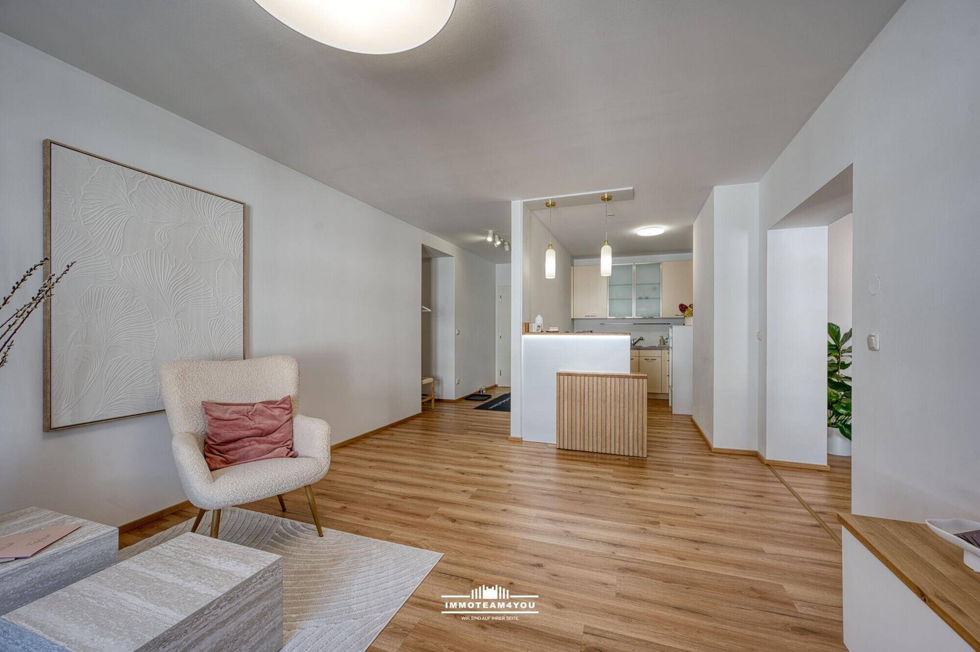 Helles Wohnzimmer mit Holzfußboden und offener Gestaltung zum Küchenbereich.