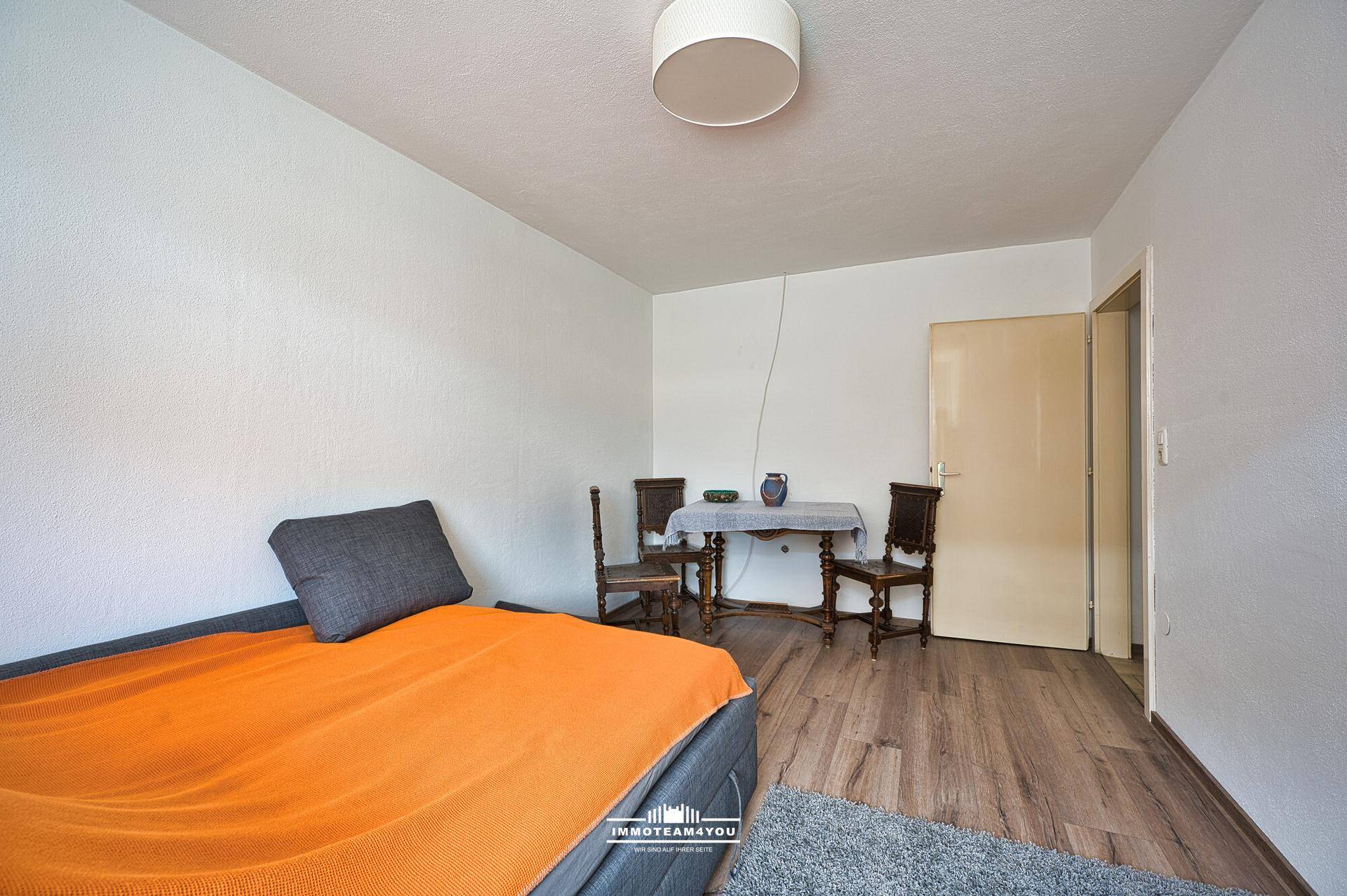Schlafzimmer mit Laminatboden, Sofa und kleinem Tisch, ideal als Gästezimmer.