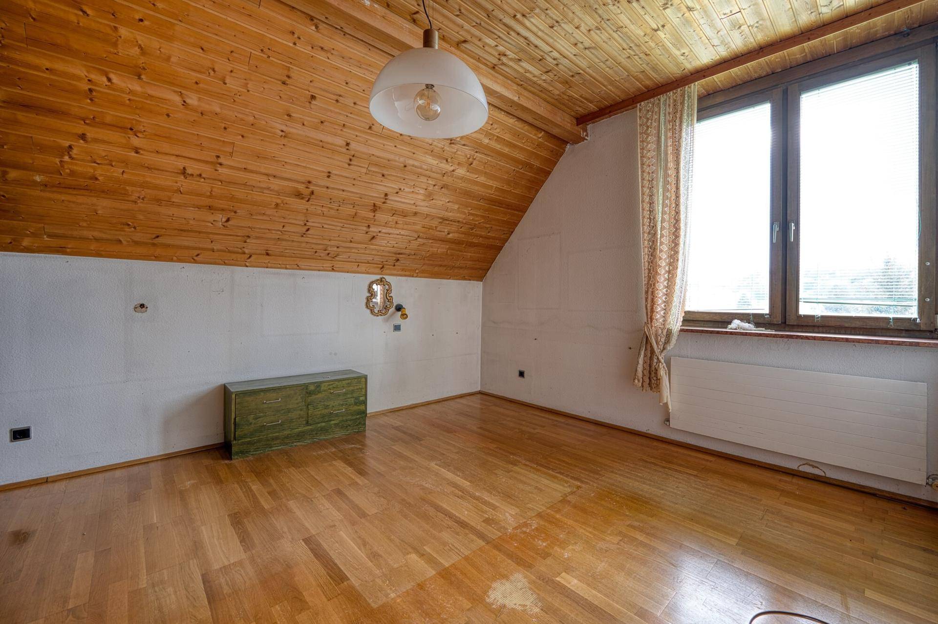 Geräumiges Dachzimmer mit Holzboden, Holzdecke und Fenster, bereit zur individuellen Gestaltung.