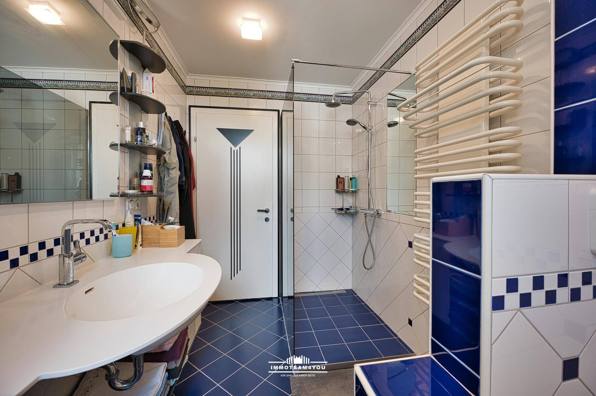 Badezimmer mit blauen und weißen Fliesen, Dusche und beheiztem Handtuchhalter.