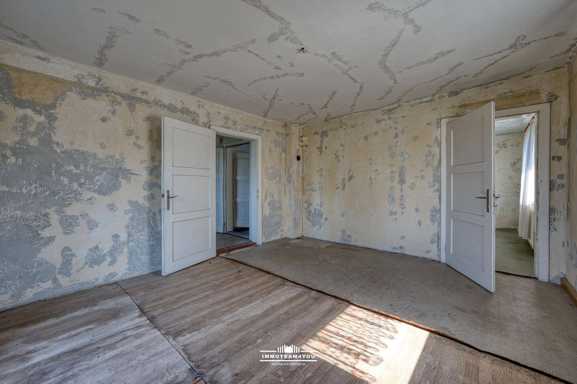 Leerer Raum mit abgenutzten Wänden und Böden, bereit für eine umfassende Renovierung.