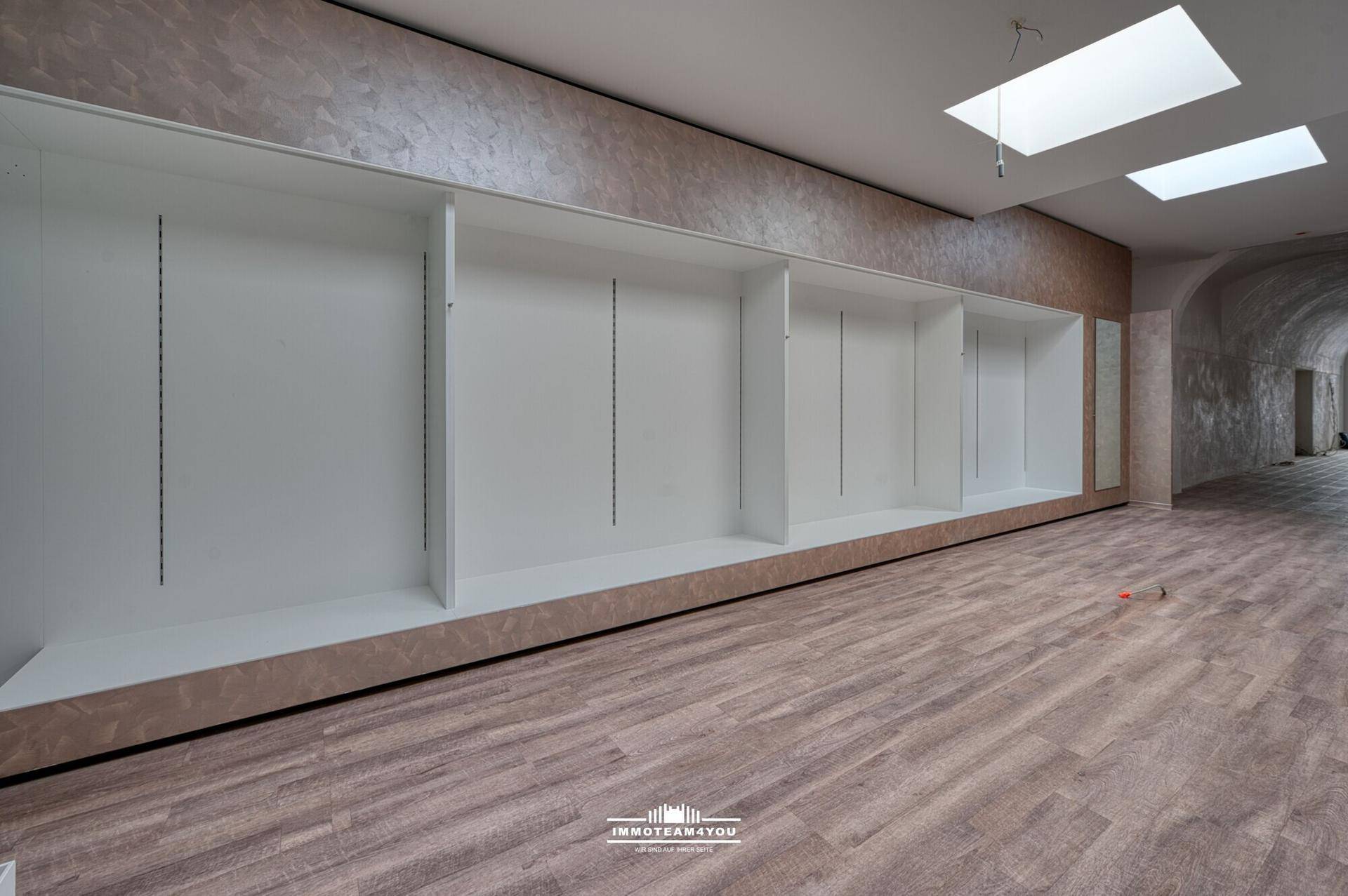 Detailansicht der Einbauregale in einem modernen Raum mit Laminatboden und Oberlichtern.