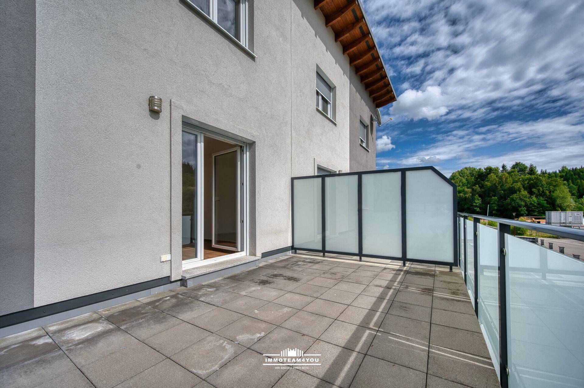 Leere Terrasse mit Fliesenboden und Zugang zum Innenbereich des Hauses.