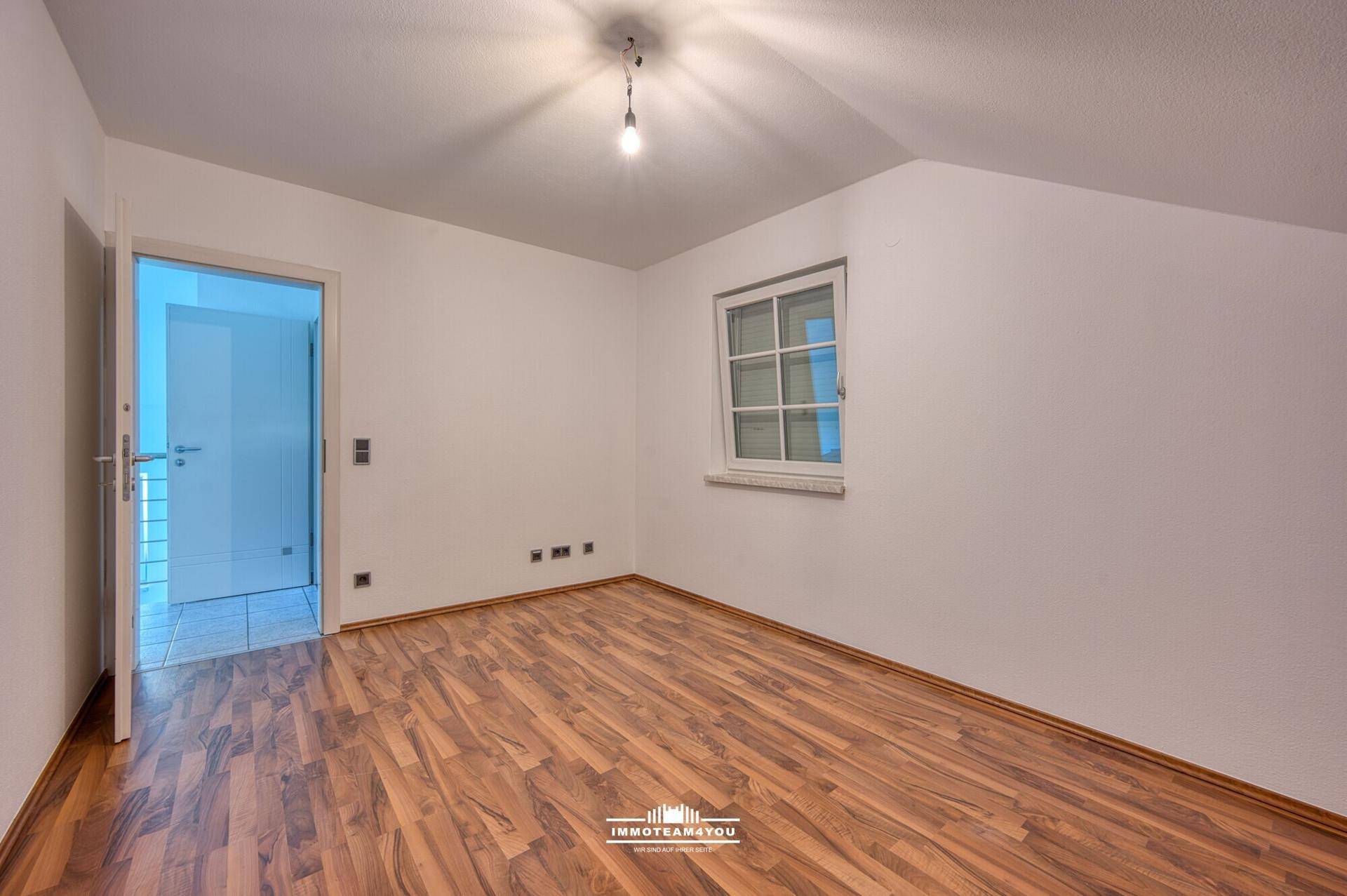 Helles Zimmer im Dachgeschoss mit Laminatboden und Fenster.