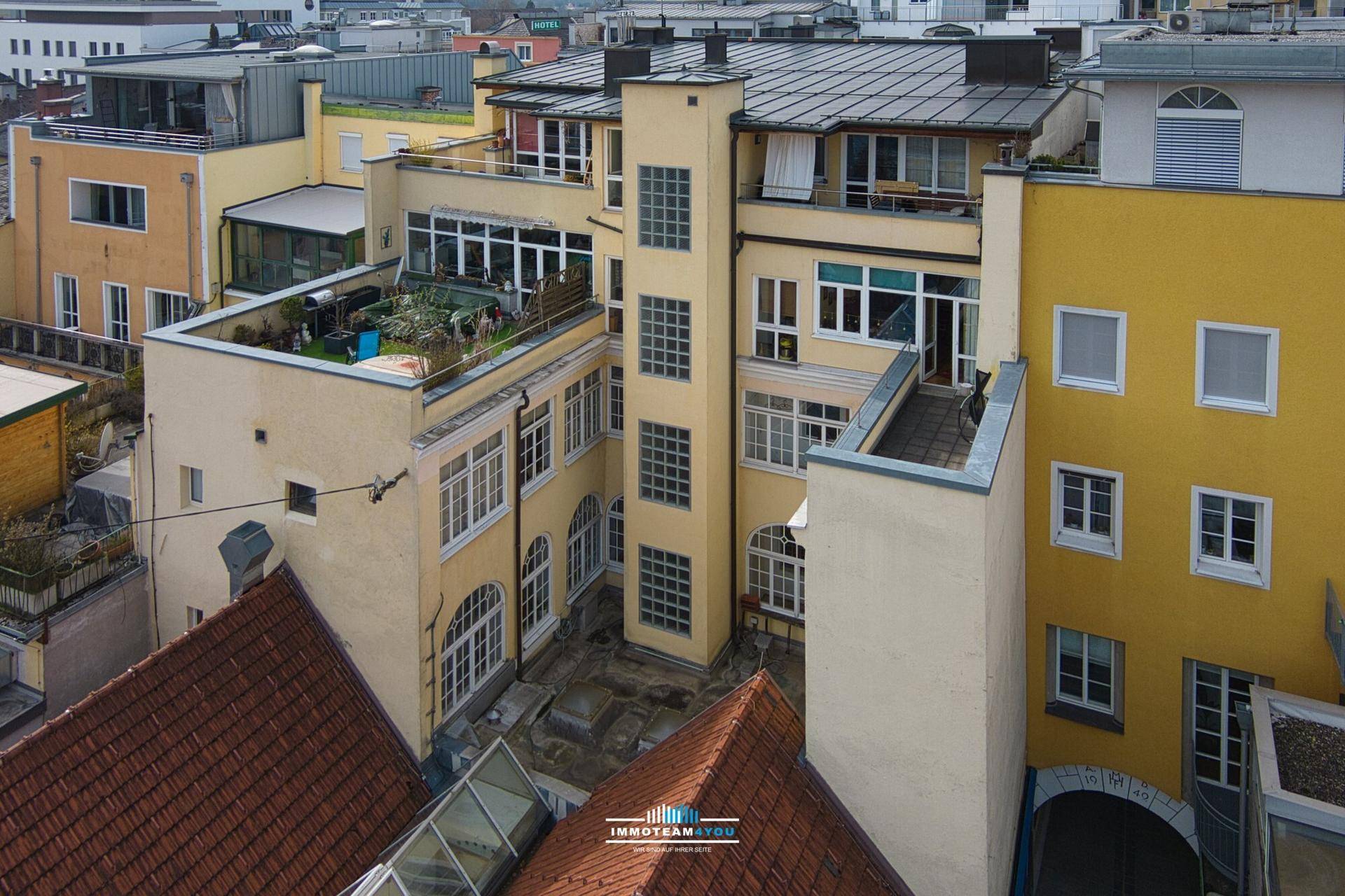 Luftaufnahme eines Innenhofs mit verschiedenen Gebäuden, Dachterrassen und architektonischen Details.
