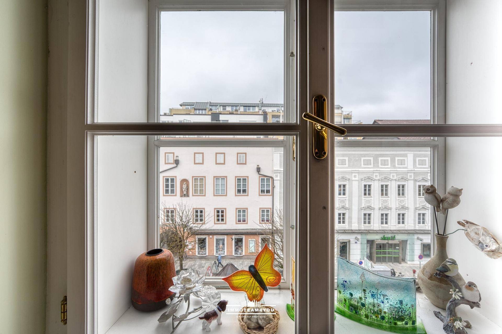 Fenster mit Blick auf die gegenüberliegenden historischen Gebäude und eine dekorative Schmetterlingsfigur.