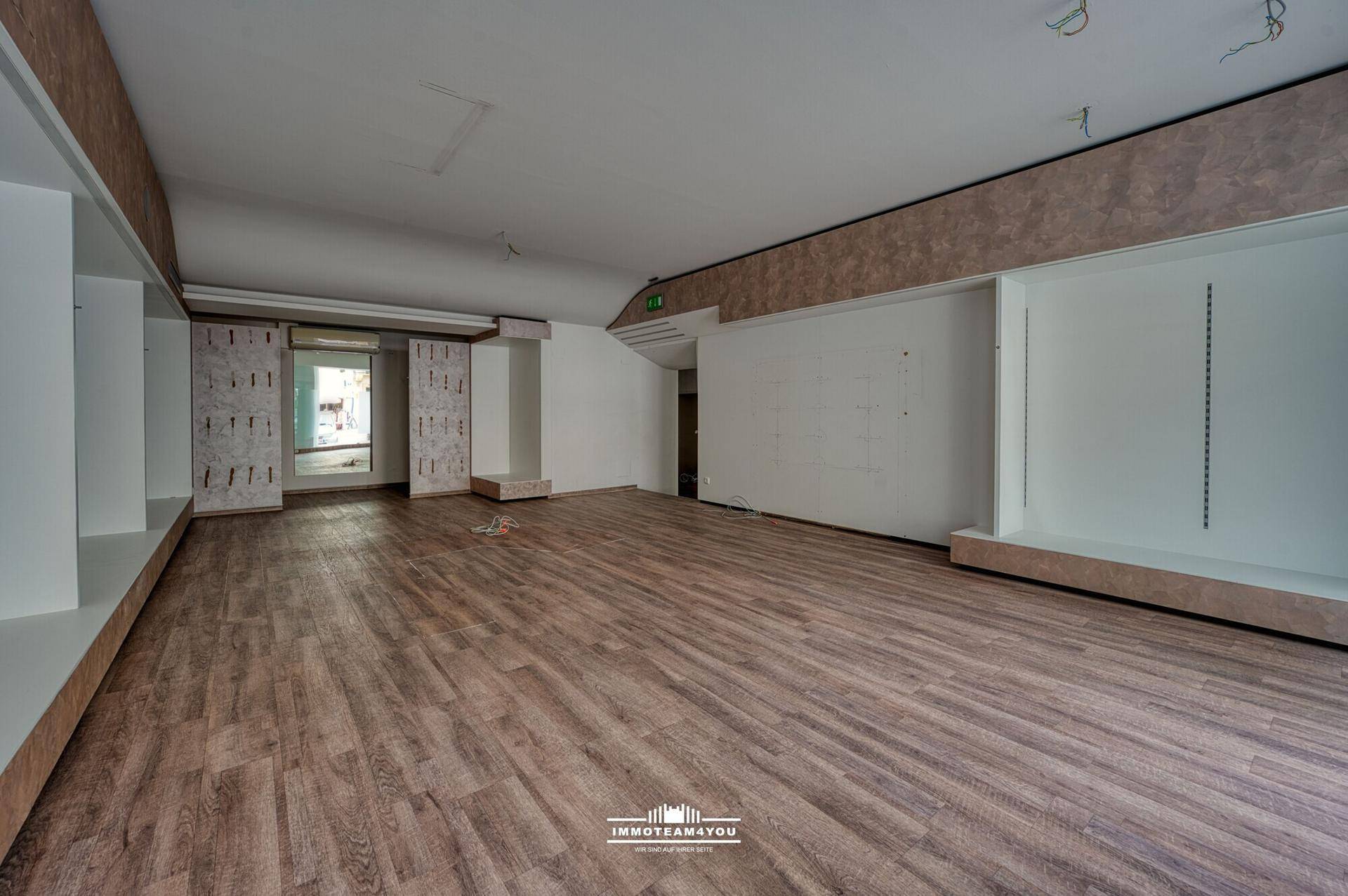 Weiterer Blick in den leeren Ladenraum mit Laminatboden und vorbereiteten Wänden für die Ladeneinrichtung.