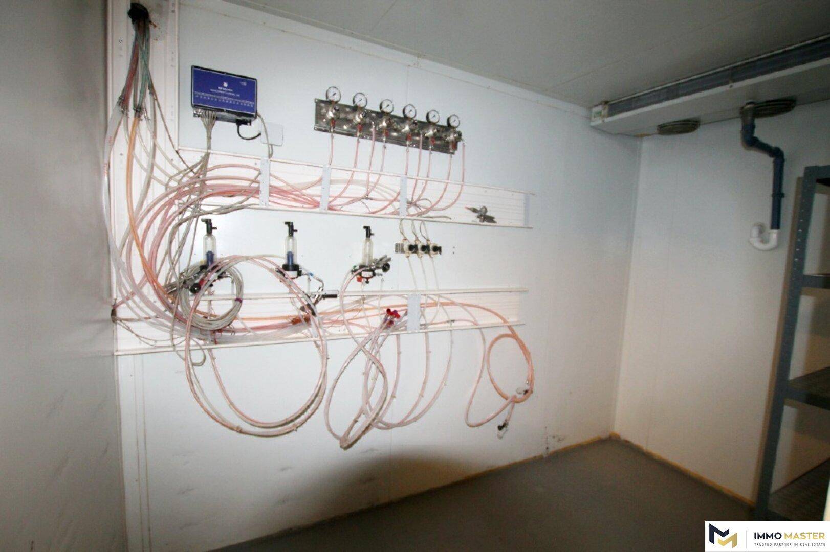 Technikraum mit umfangreicher Verrohrung und Steuerungselementen, wahrscheinlich für Getränkeausschank.