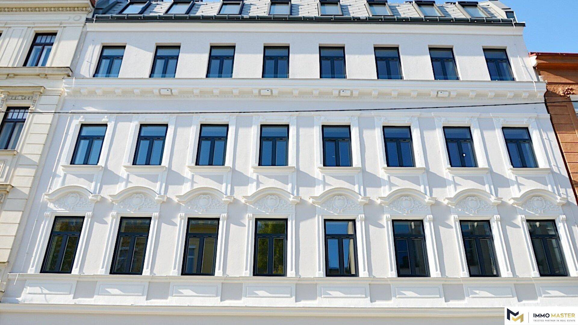 Klassische Altbaufassade mit vielen Fenstern und dekorativen Elementen, gut erhalten.