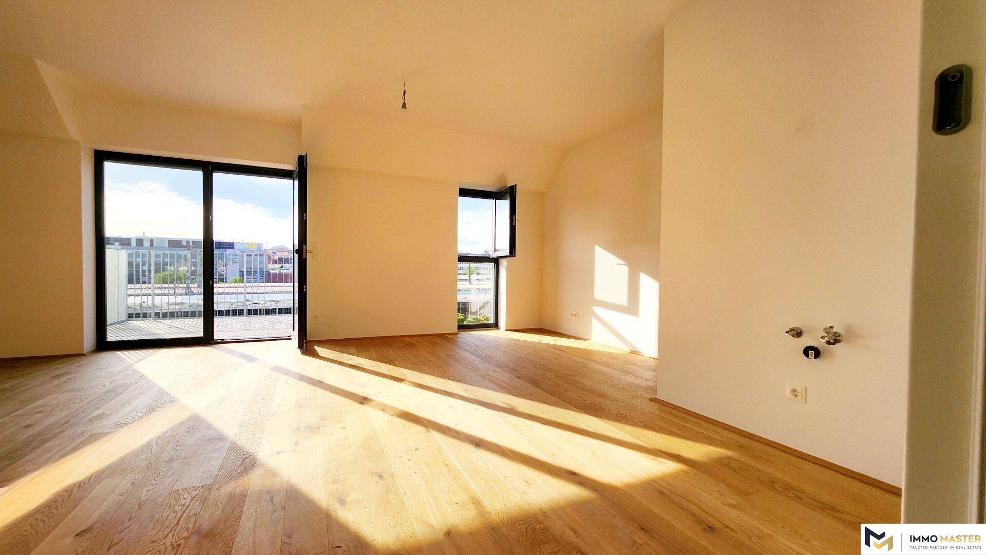 Lichtdurchfluteter Raum mit Holzboden und Zugang zu einem Außenbereich, vorbereitet für eine Küche.