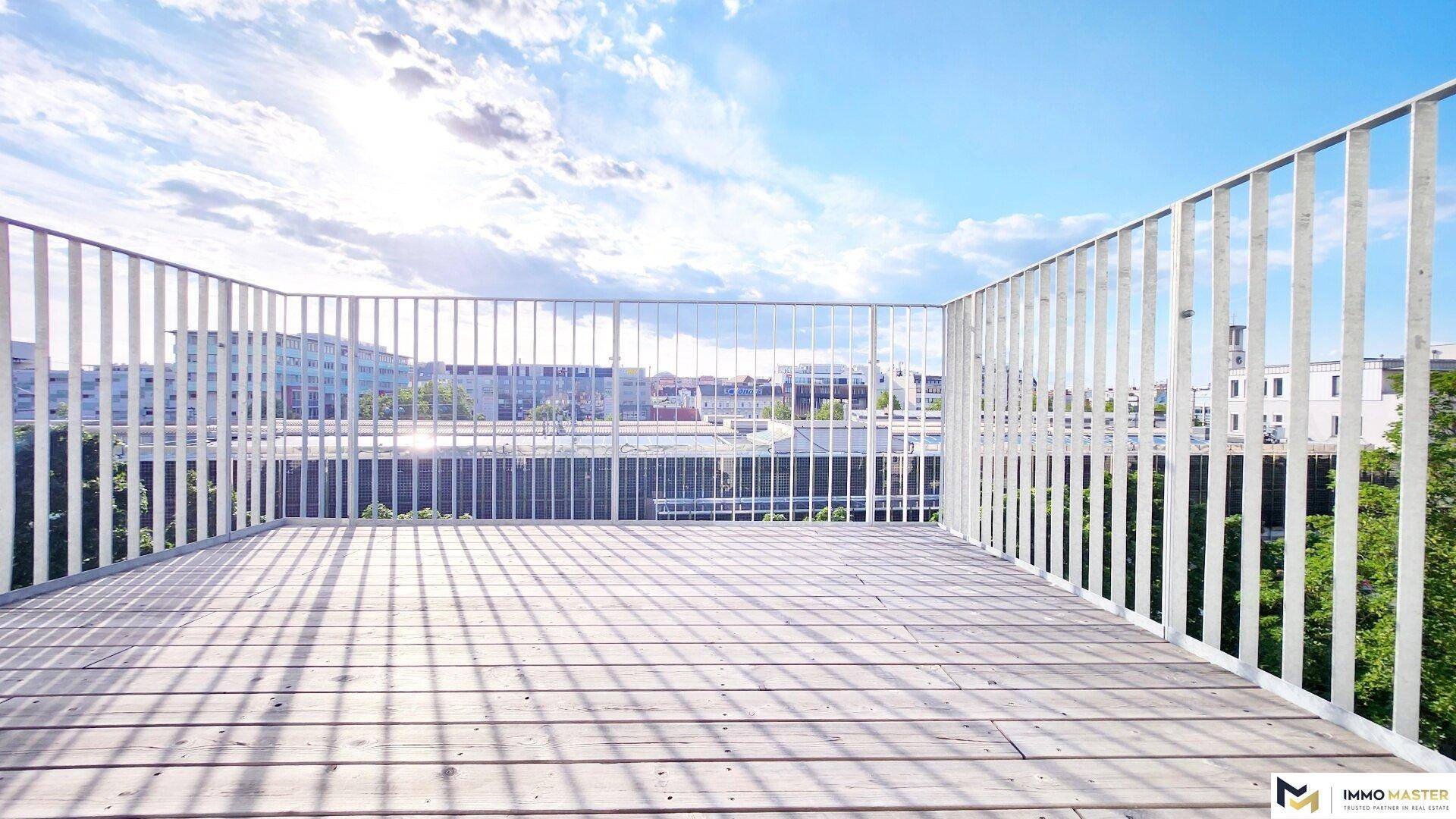 Sonniger Außenbereich mit Holzdeck und modernem Geländer, ideal für Entspannung im Freien.