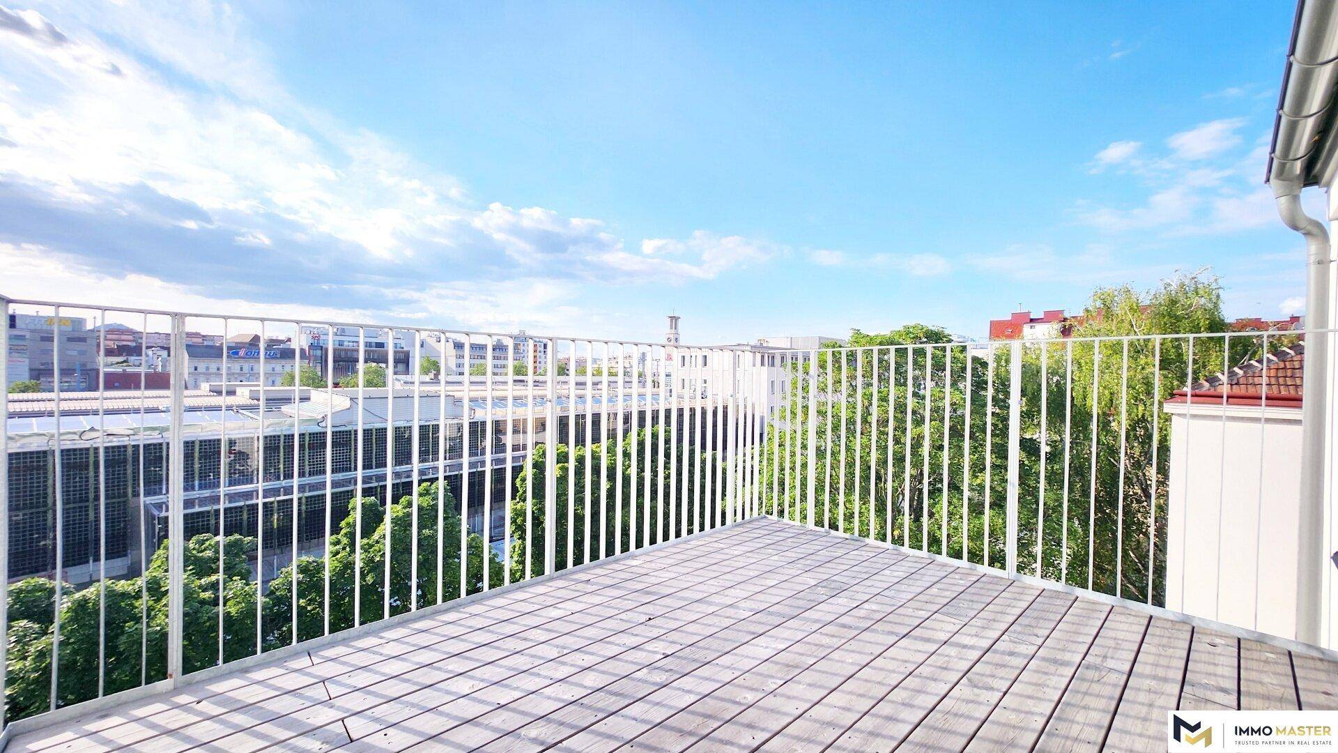 Geräumige Holzterrasse mit weißem Geländer und weitem Blick über die Stadtlandschaft.