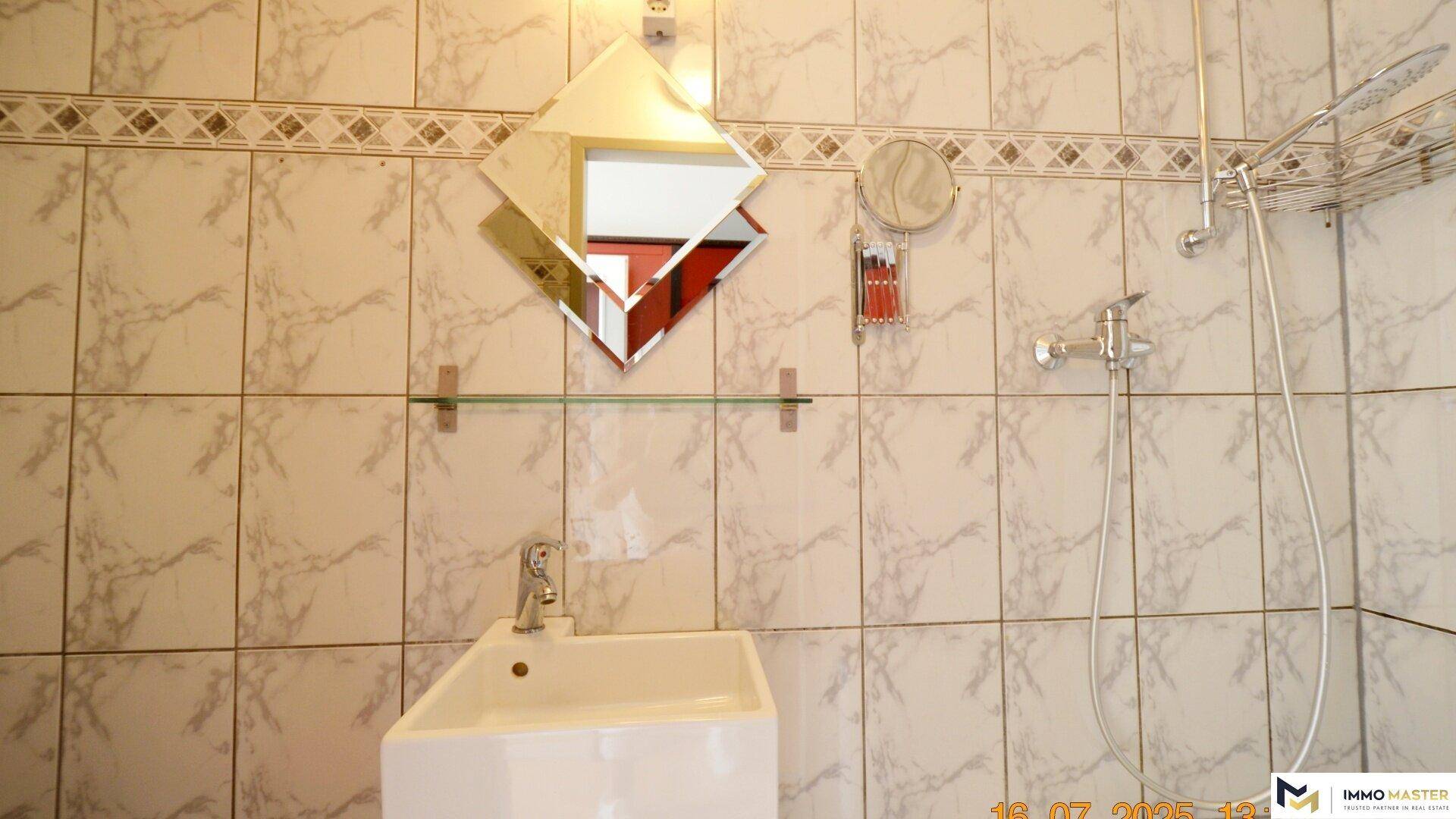 Modernes Badezimmer mit Duschwanne, Waschbecken und dekorativen Fliesen an den Wänden.
