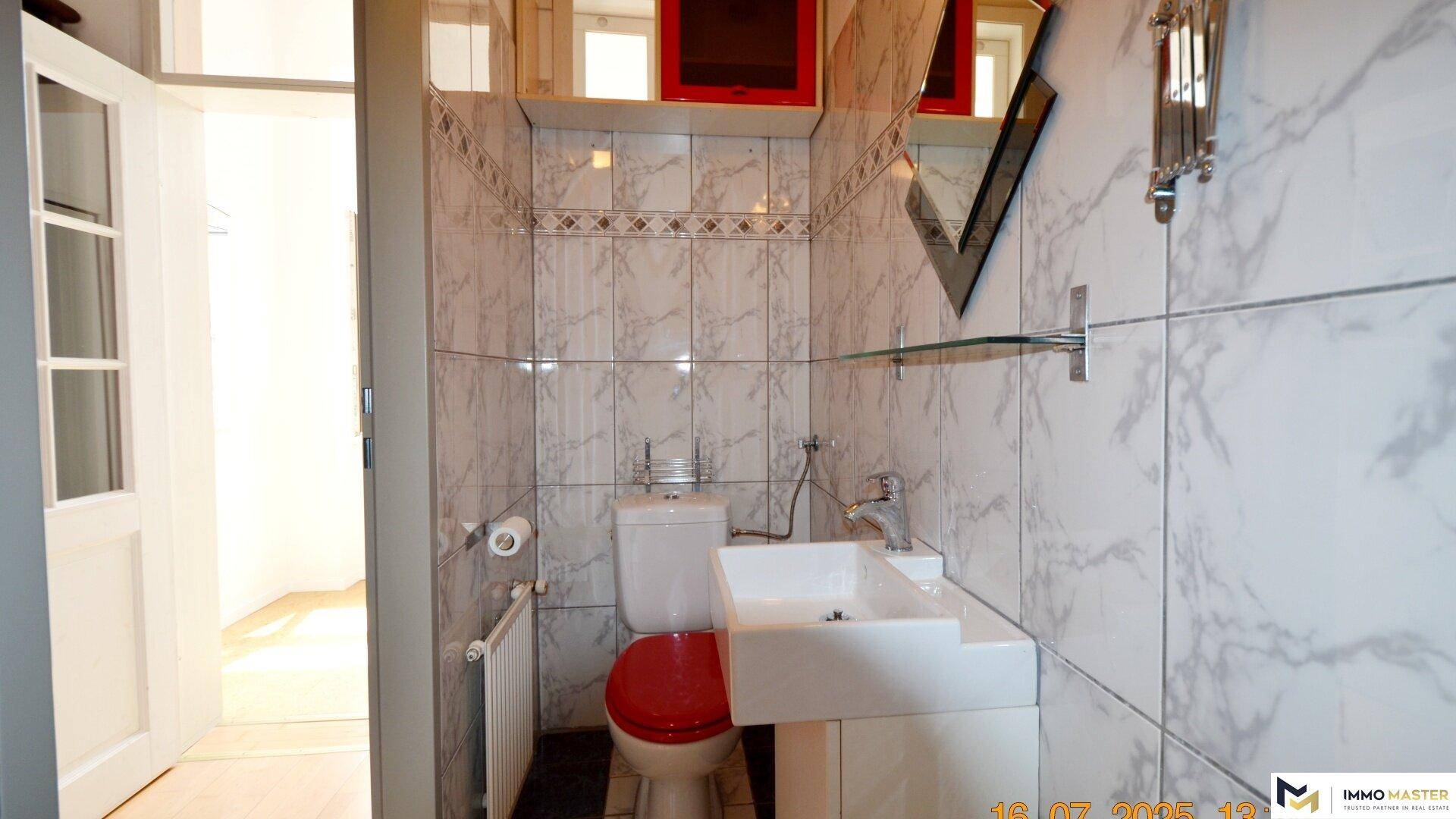 Separate Toilette mit Waschbecken und Spiegel, ausgestattet mit hellen Marmorfliesen.