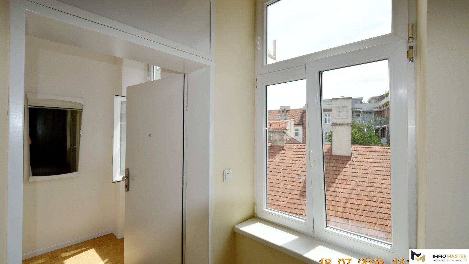 Heller Flur mit Fenster und Blick auf die Dächer, der den Eingangsbereich erhellt.