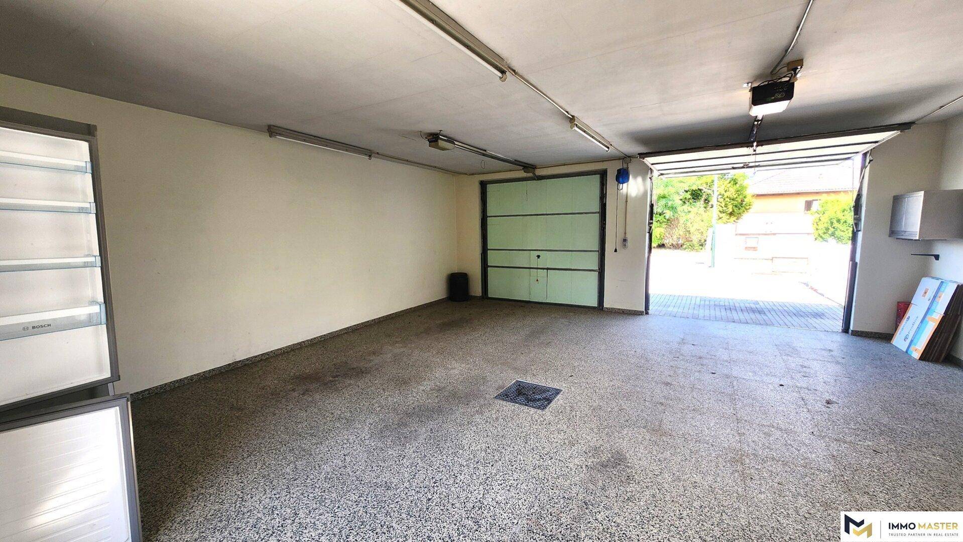 Geräumige Garage mit Rolltor und ausreichend Platz für Fahrzeuge und Lagerung.