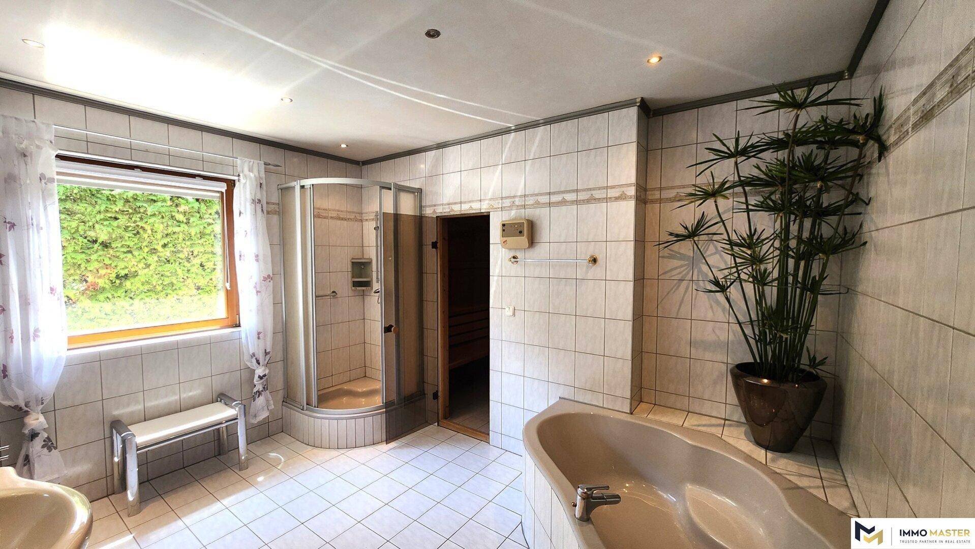 Großes Badezimmer mit Badewanne, Duschkabine, Fenster und integrierter Sauna.