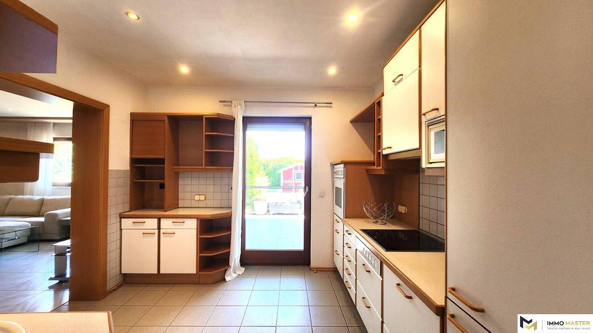 Funktionale Küche mit Einbauschränken, Kochfeld und direktem Zugang zur Terrasse.