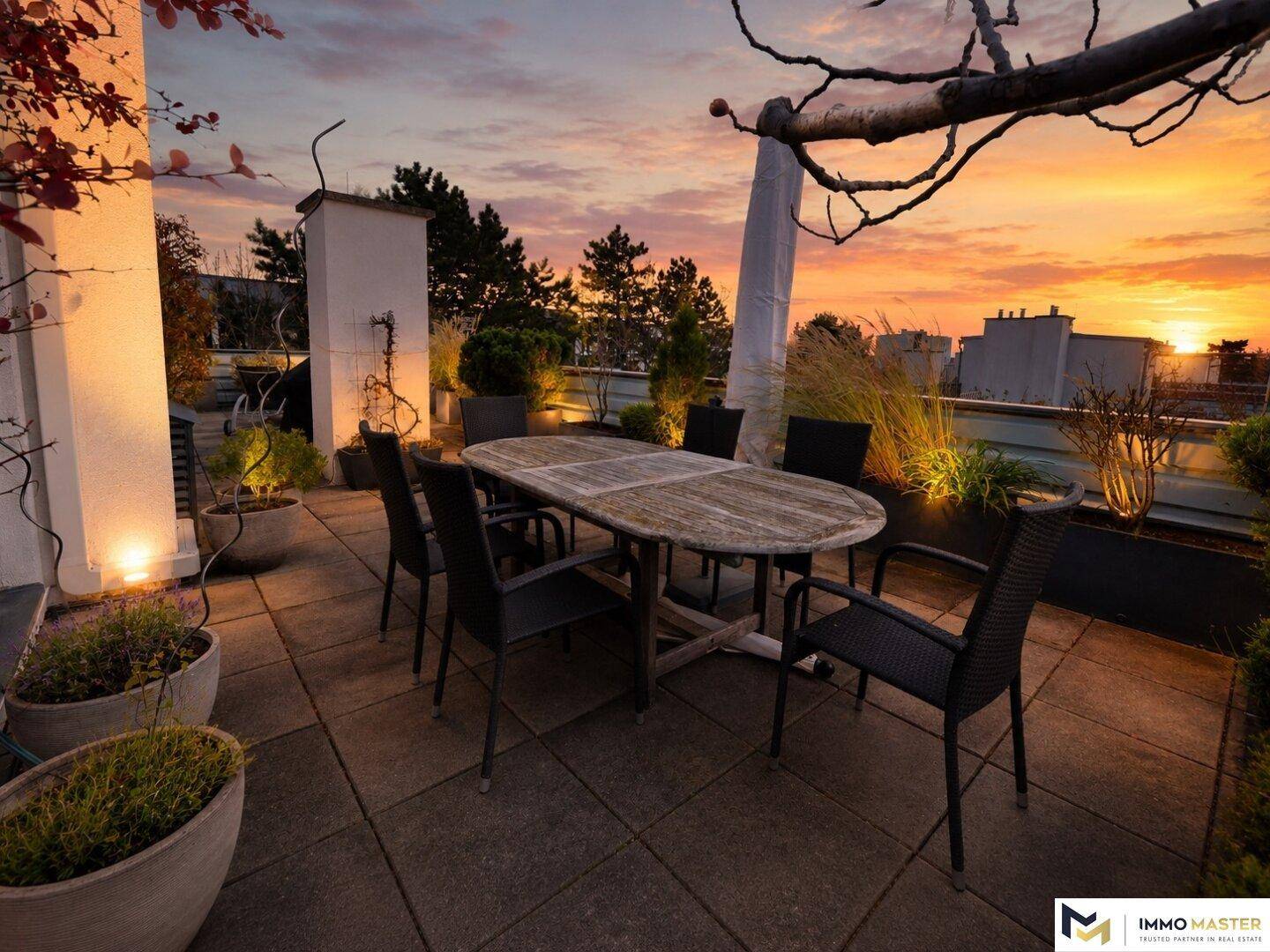 Stimmungsvolle Dachterrasse bei Sonnenuntergang mit Esstisch und malerischem Blick über die Stadt.