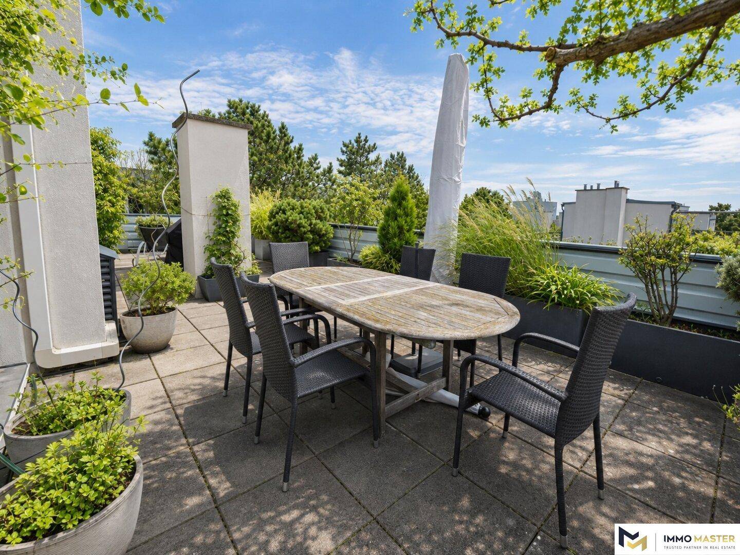 Geräumige Dachterrasse mit Esstisch und üppiger Bepflanzung, ideal für Entspannung im Freien.