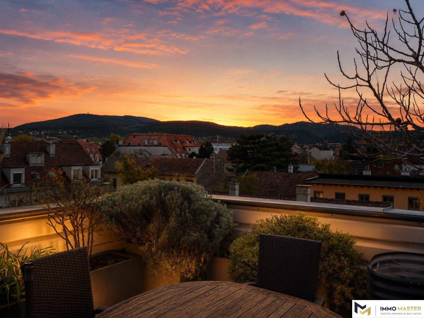 Atemberaubender Sonnenuntergang von der Dachterrasse mit Blick auf die Stadt und die umliegende Berglandschaft.