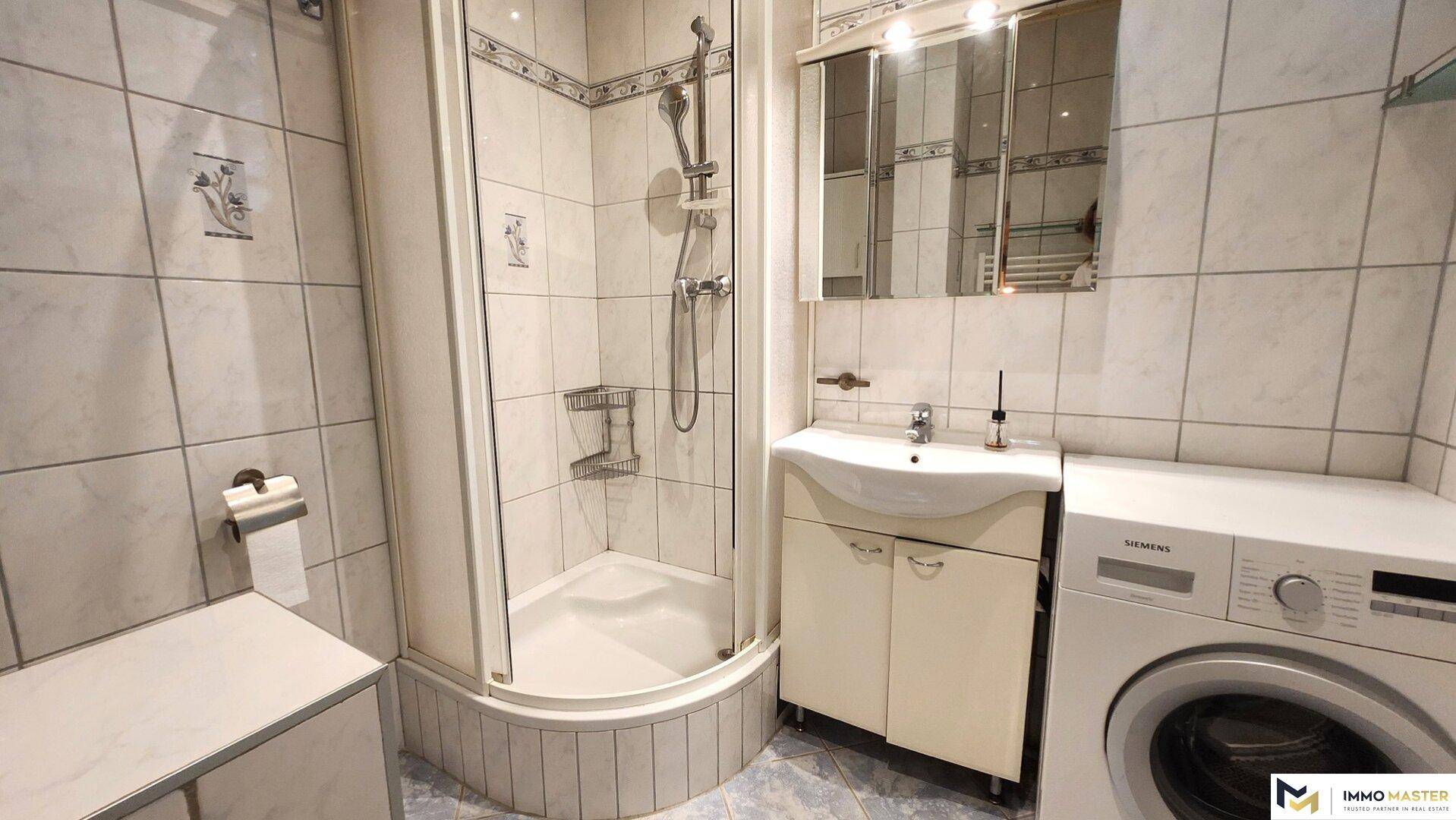 Älteres Badezimmer mit Duschkabine, Waschbecken und Spiegelschrank.
