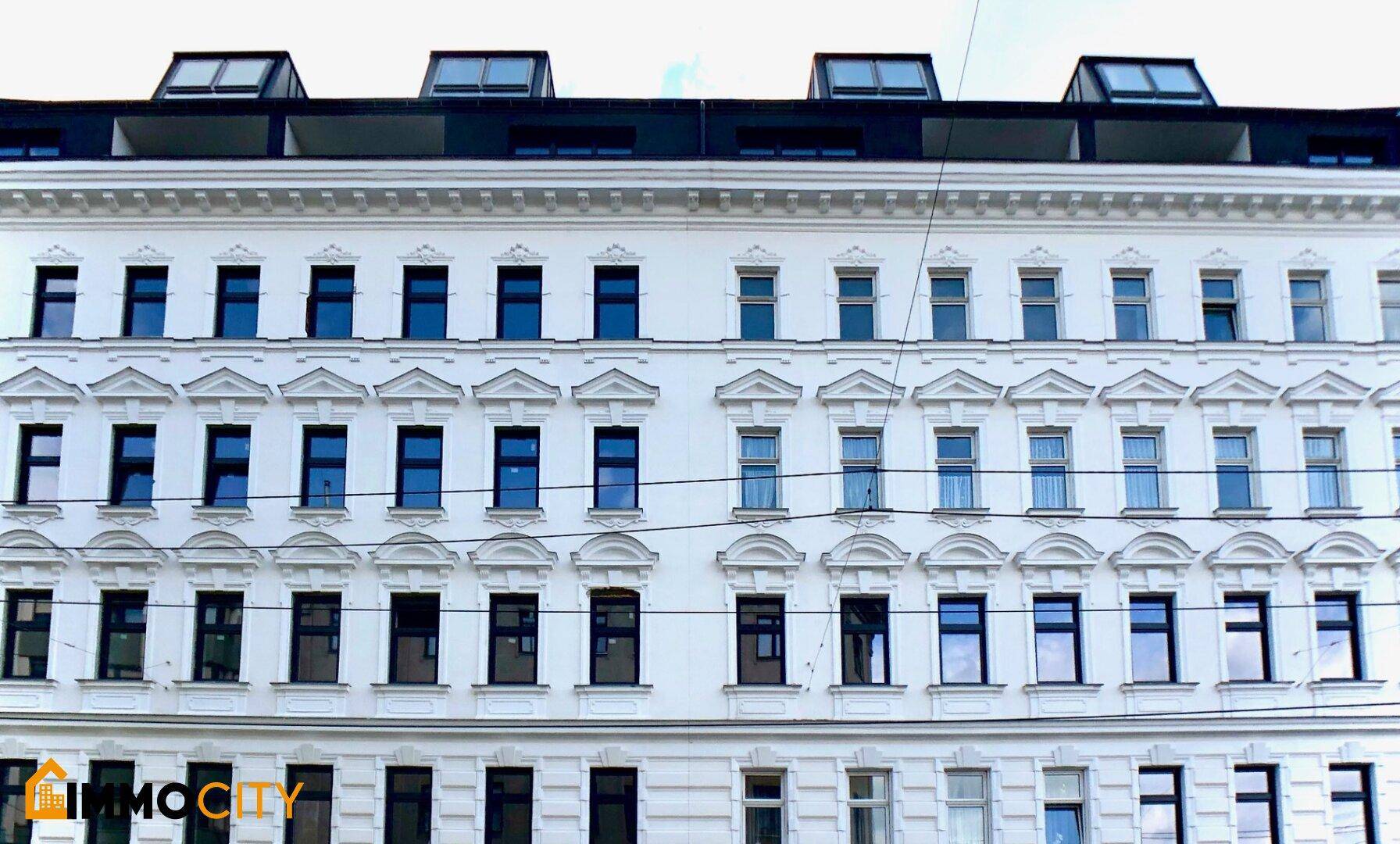 Historische Gebäudefassade mit vielen Fenstern und modernen Dachausbauten, die den Charme bewahren.