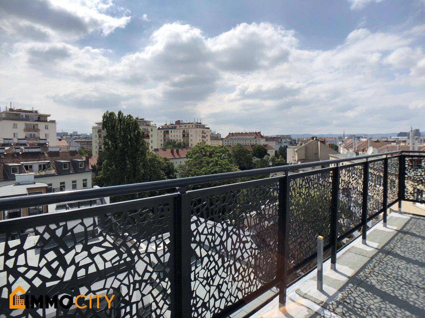 Dachterrasse mit modernem, gemustertem Geländer und weitem Blick über die Stadt.