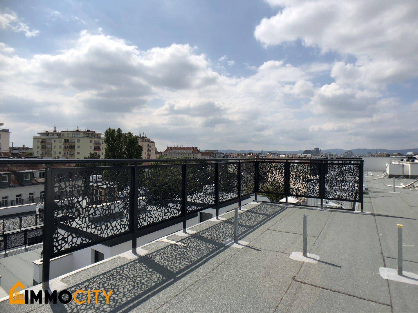 Weitläufige Dachterrasse mit modernem Geländer und Panoramablick über die Stadt.