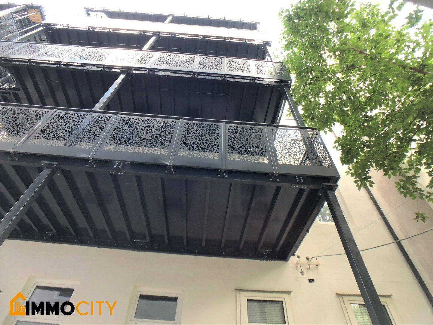 Mehrere Balkone mit dekorativen Metallgeländern, von unten betrachtet.