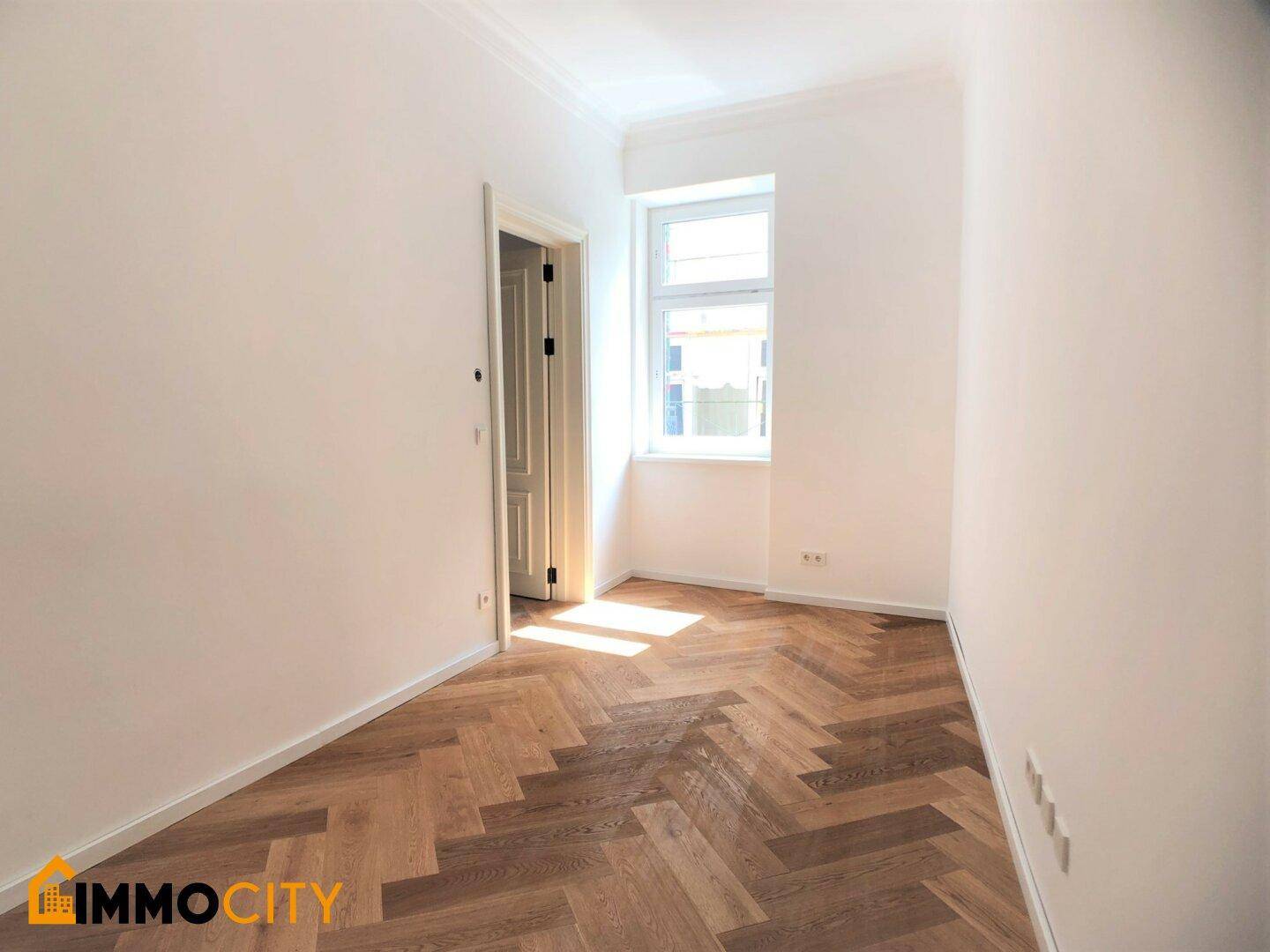 Gemütliches Zimmer mit Fischgrätparkett und einem Fenster, ideal als Schlafzimmer.