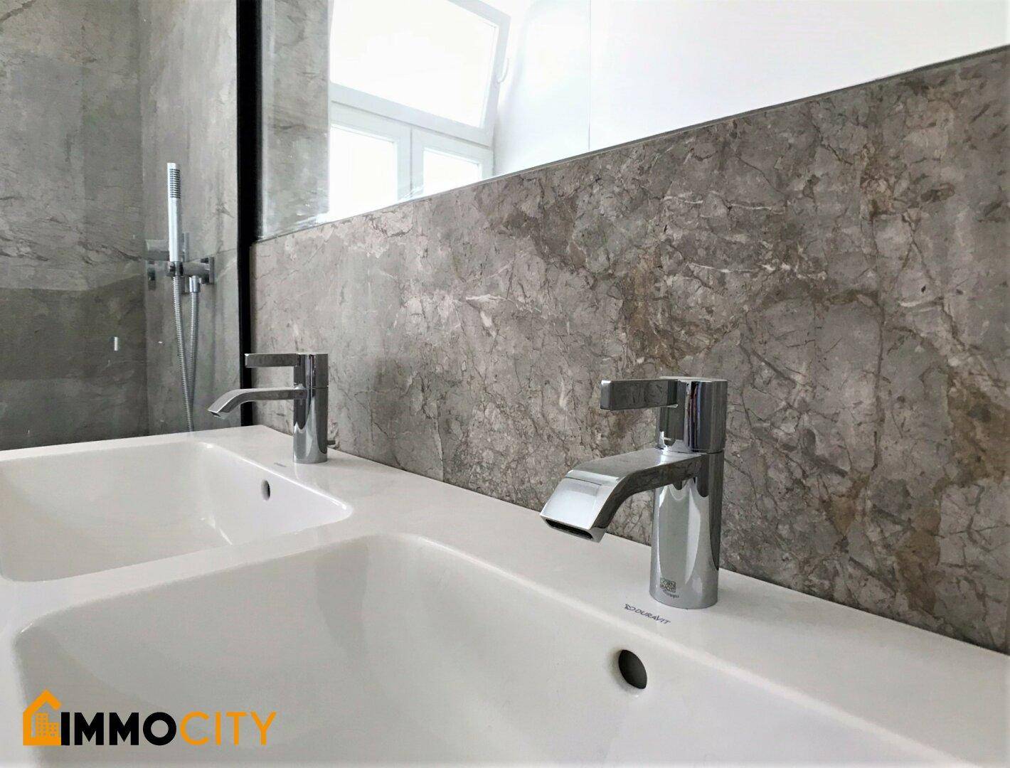 Modernes Badezimmer mit Doppelwaschbecken und grauen Marmorfliesen an der Wand, minimalistisches Design.