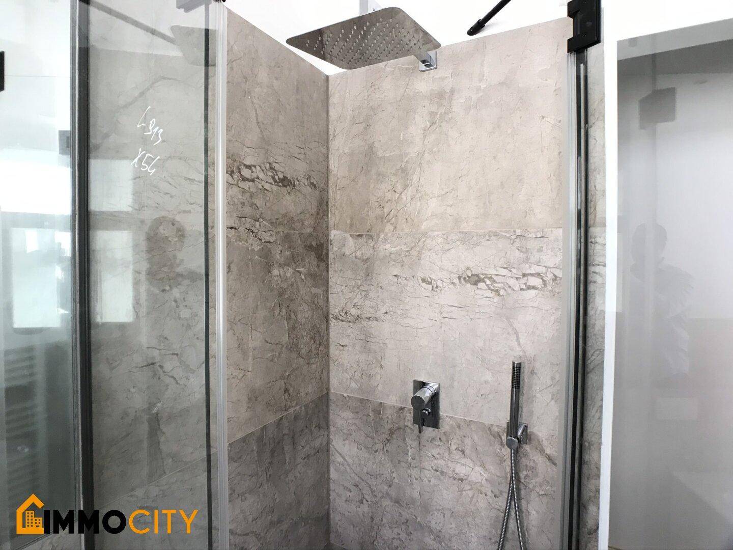 Moderne Duschkabine mit Regendusche und eleganten grauen Fliesen im Badezimmer.
